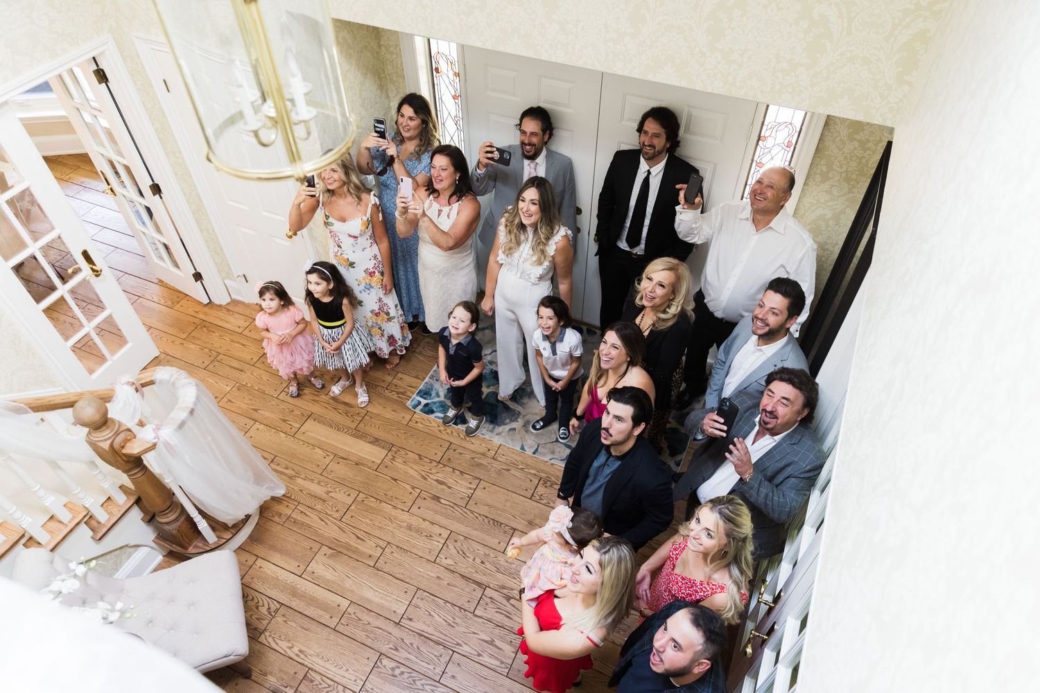 Wedding party gathered on staircase looking upward during celebration moment.