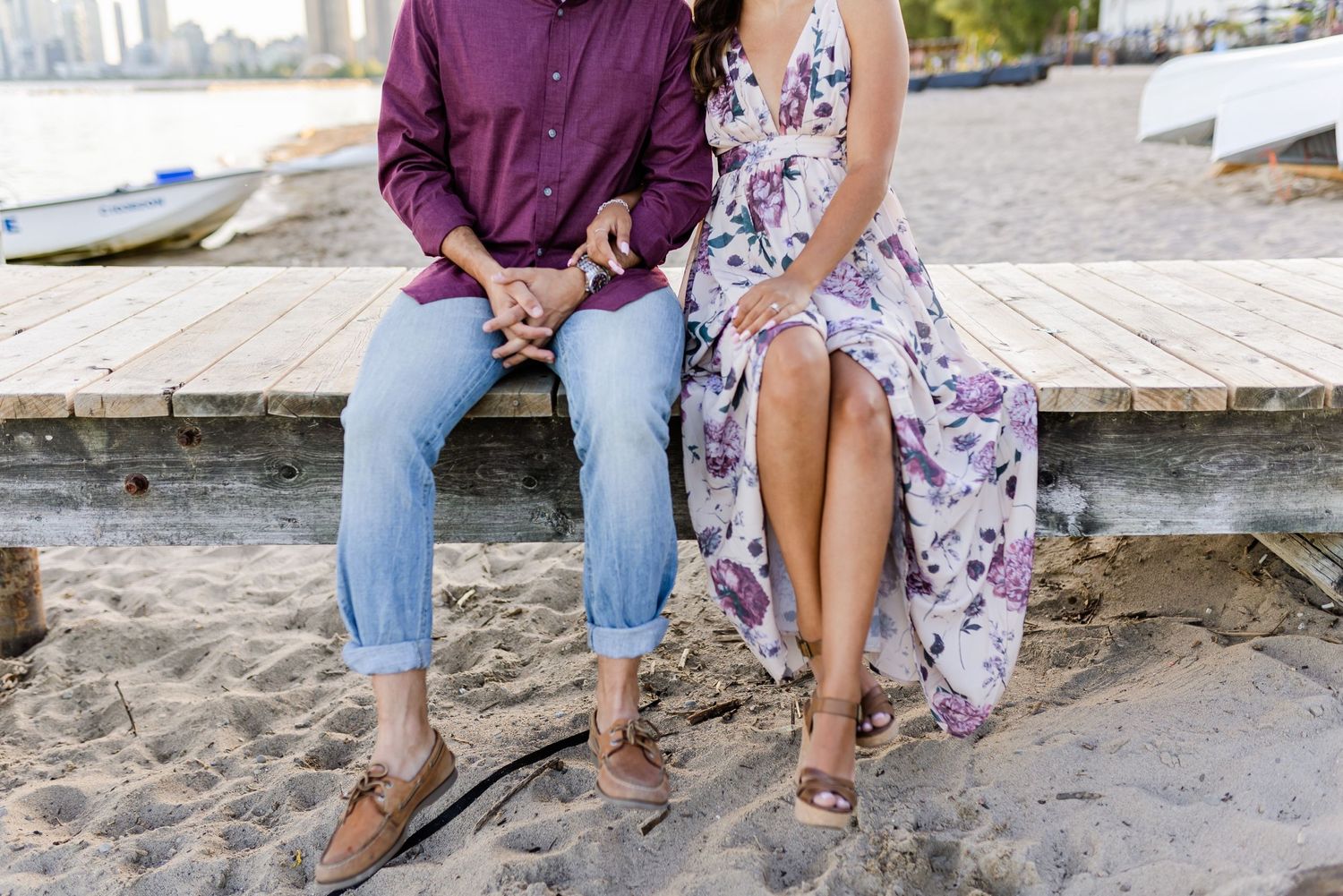Legs dangling off wooden dock showing casual shoes and summer outfits.