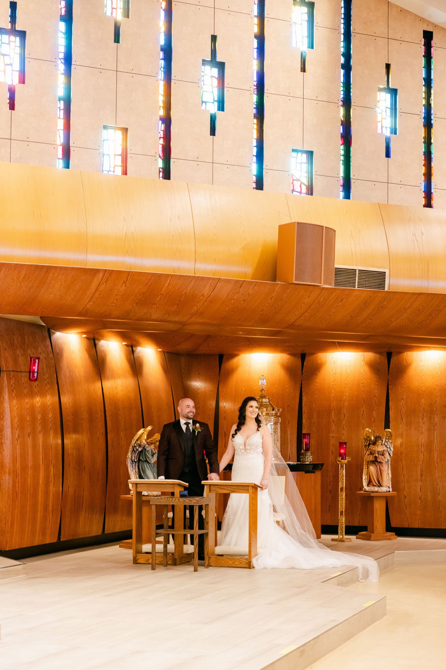 Wedding ceremony in modern sanctuary with distinctive vertical stained glass and wooden walls.