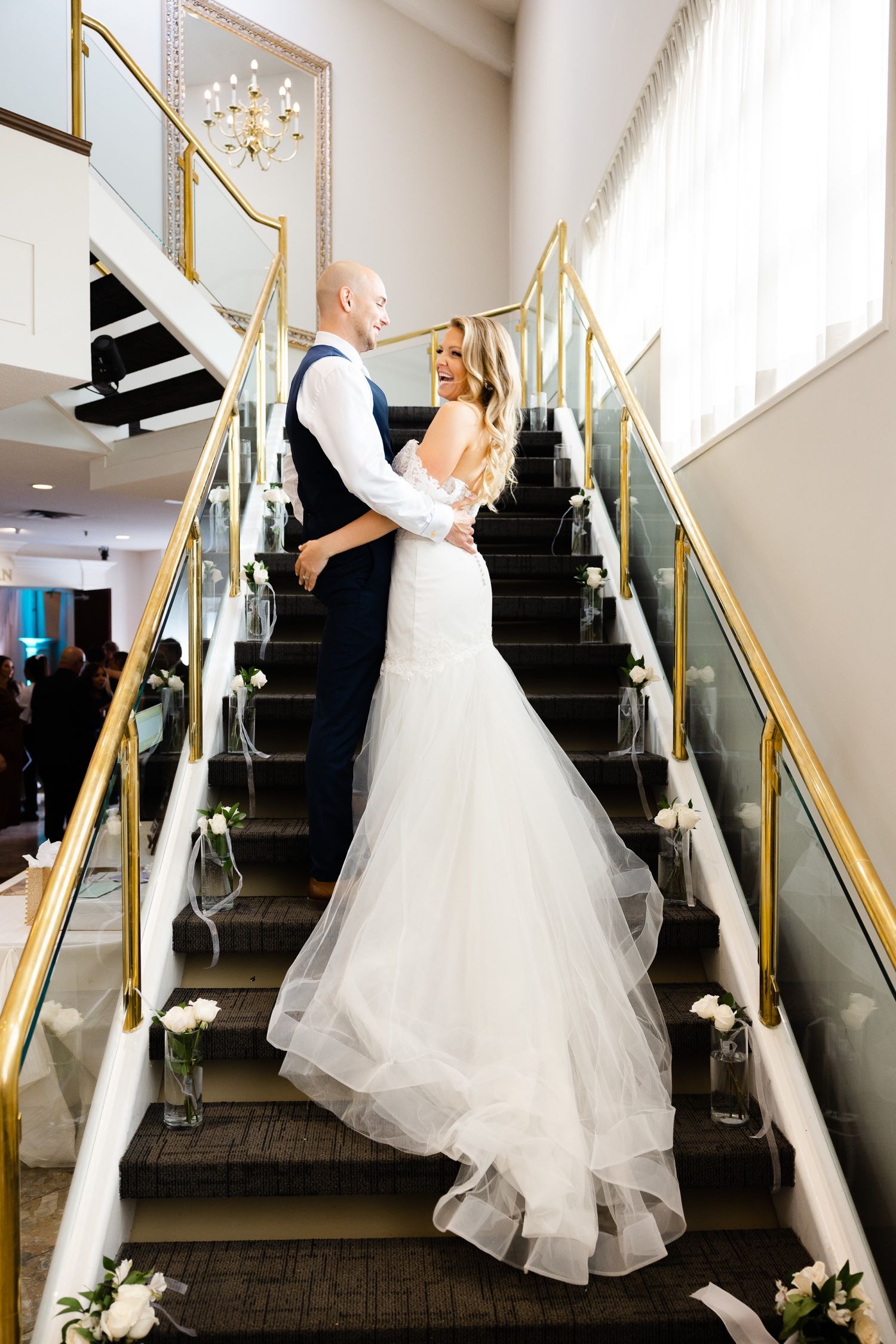 Romantic wedding moment captured on a decorated staircase with gold railings.