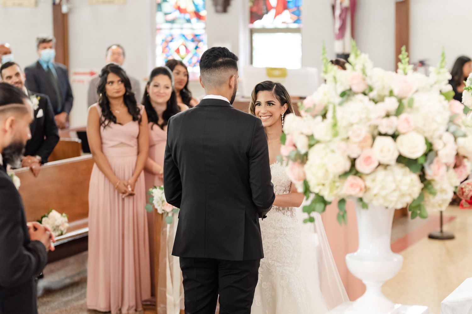 A wedding ceremony in progress with bridesmaids in pink dresses watching from the side.