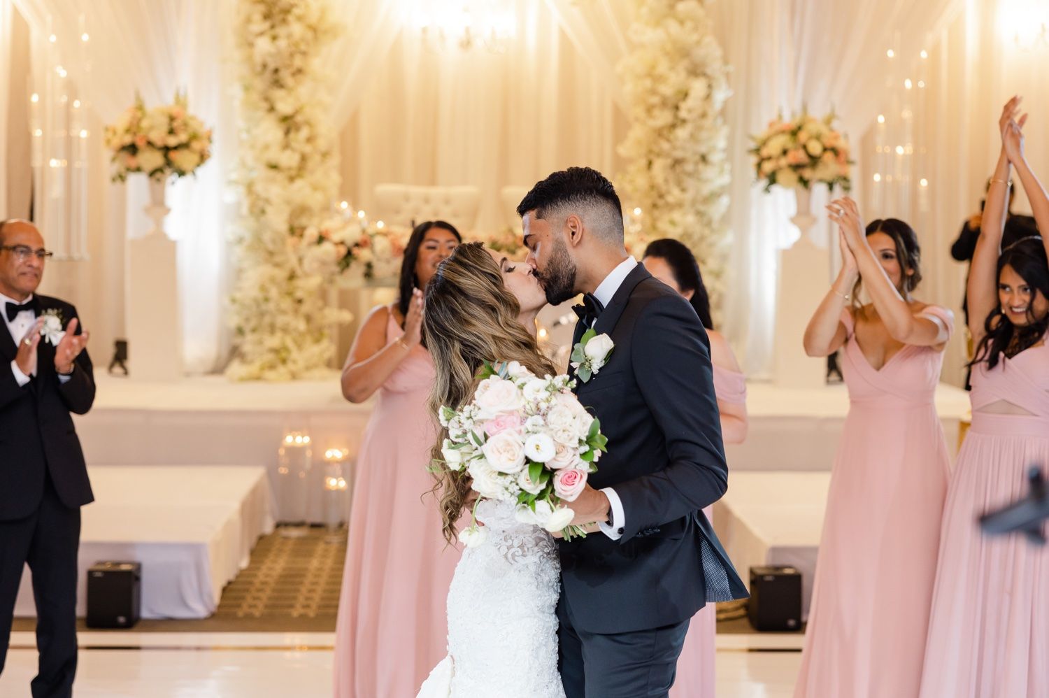 Wedding celebration moment in an elegant white and gold ballroom with floral arrangements.