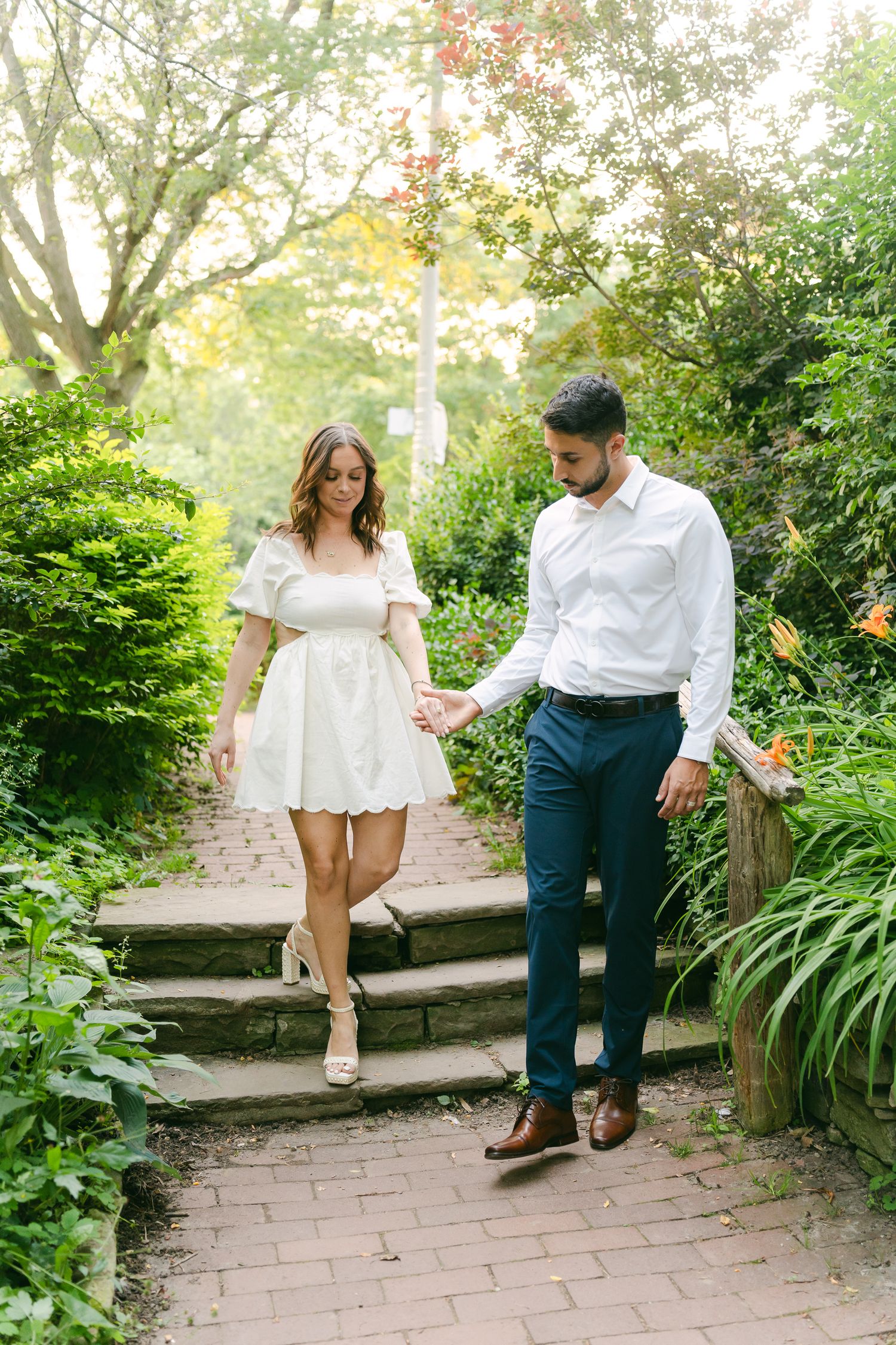 Couple descending stone garden steps surrounded by lush summer greenery.