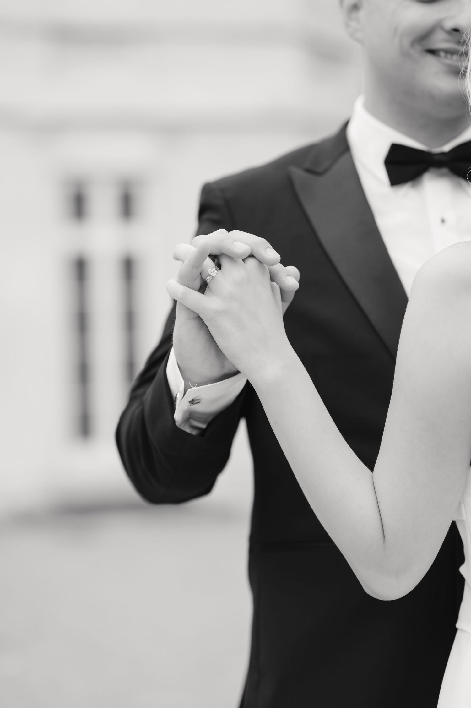 Close-up of couple's hands clasped together during first dance with formal attire.