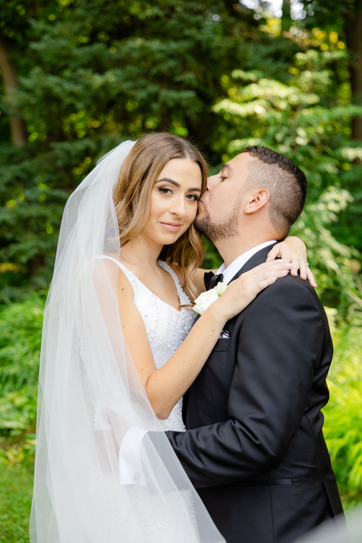 A tender wedding moment captured in a wooded setting with beautiful natural lighting.