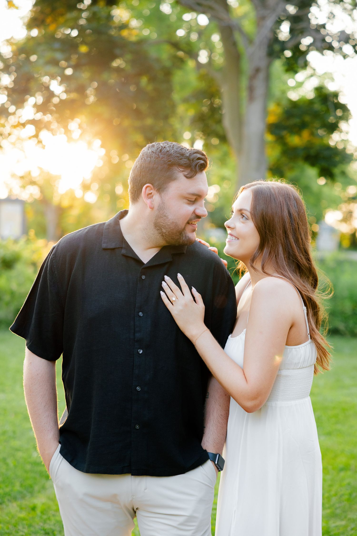 Couple shares tender moment in park with beautiful golden sunlight filtering through trees.