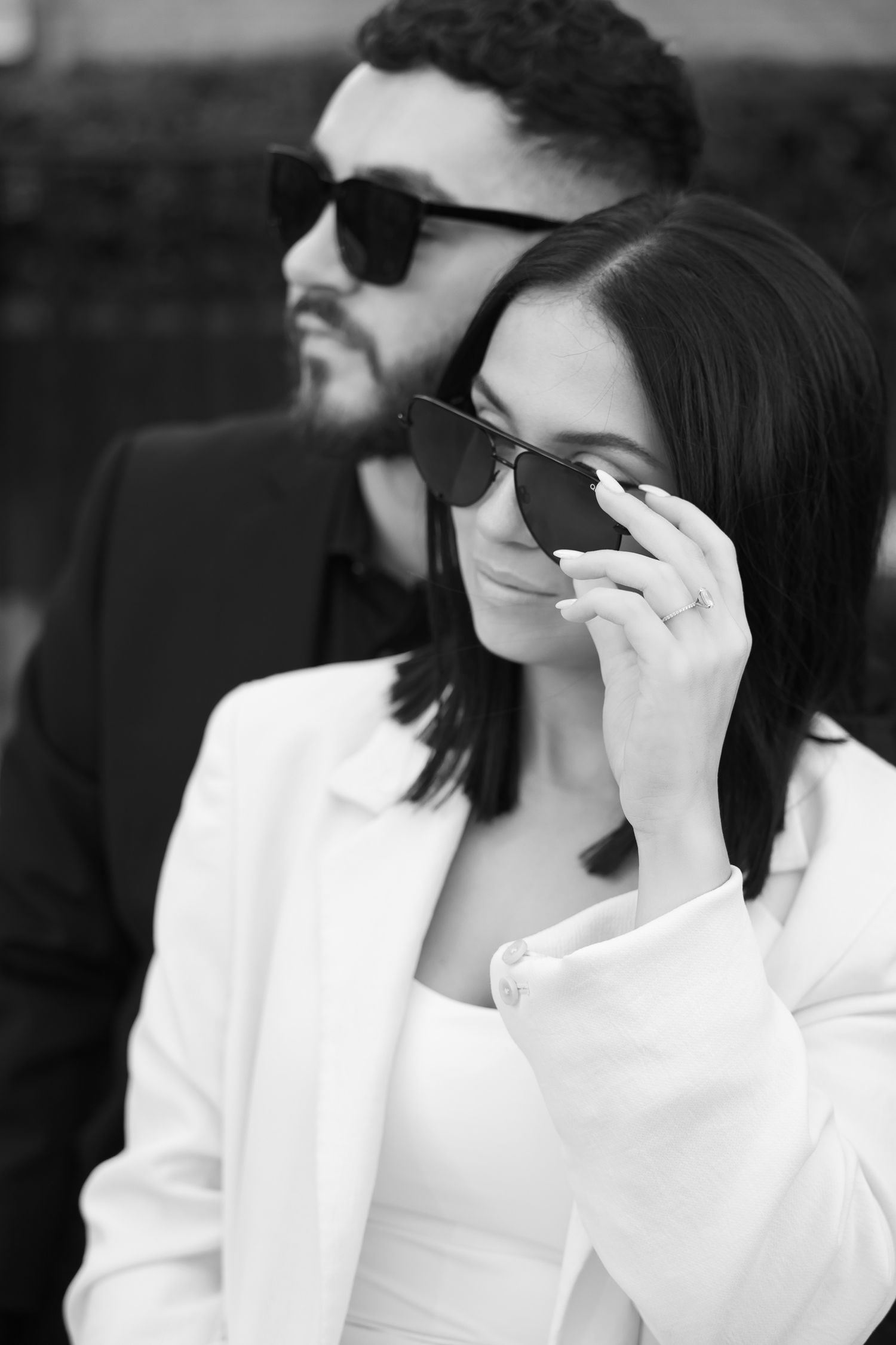 Stylish couple wearing sunglasses in black and white portrait outside Chanel.