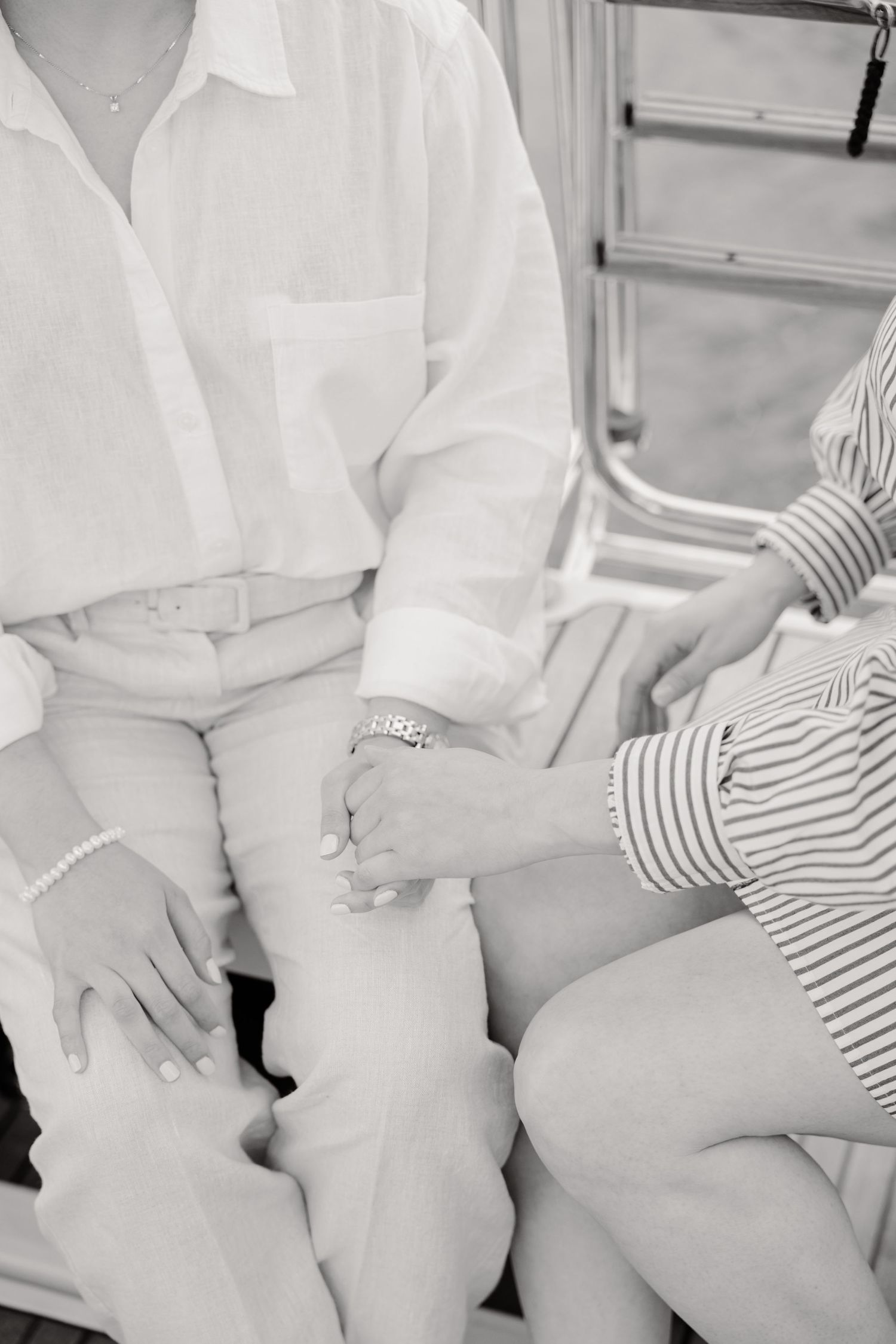 A black and white candid photo showing two people sitting together in casual attire, with one wearing a white button-down shirt.