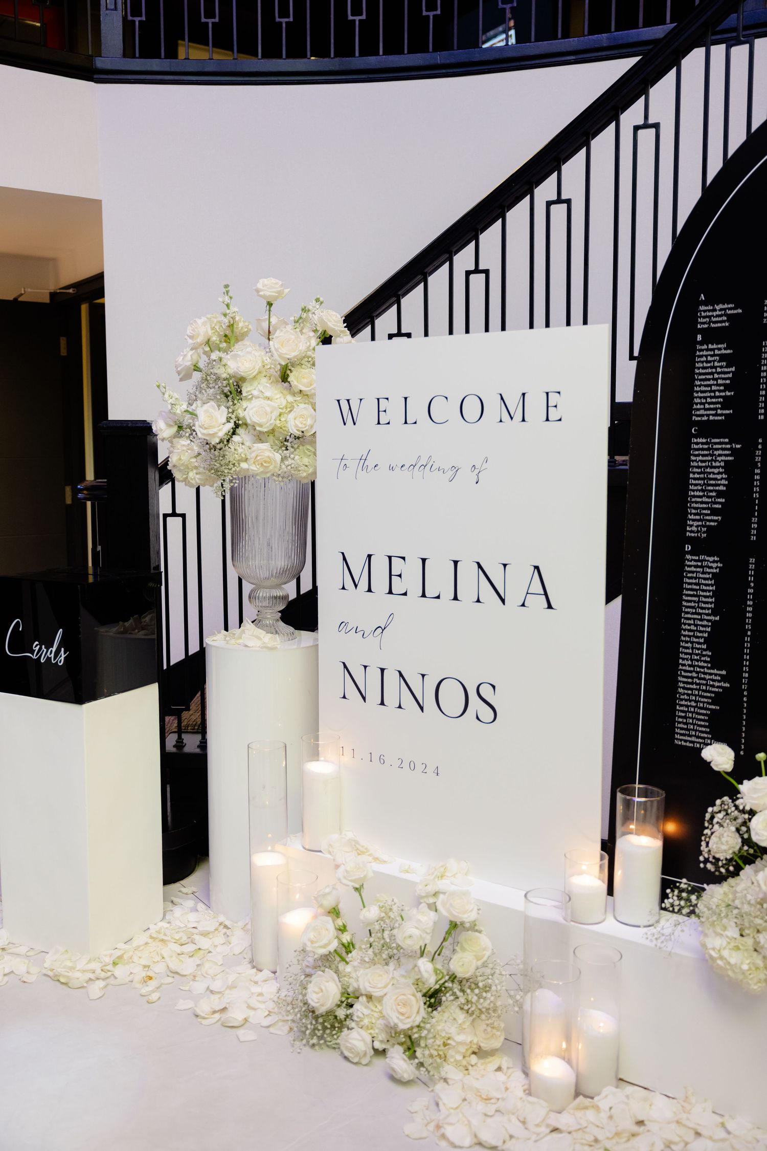 Elegant wedding welcome sign with white floral arrangements and candles creating a romantic entrance display.