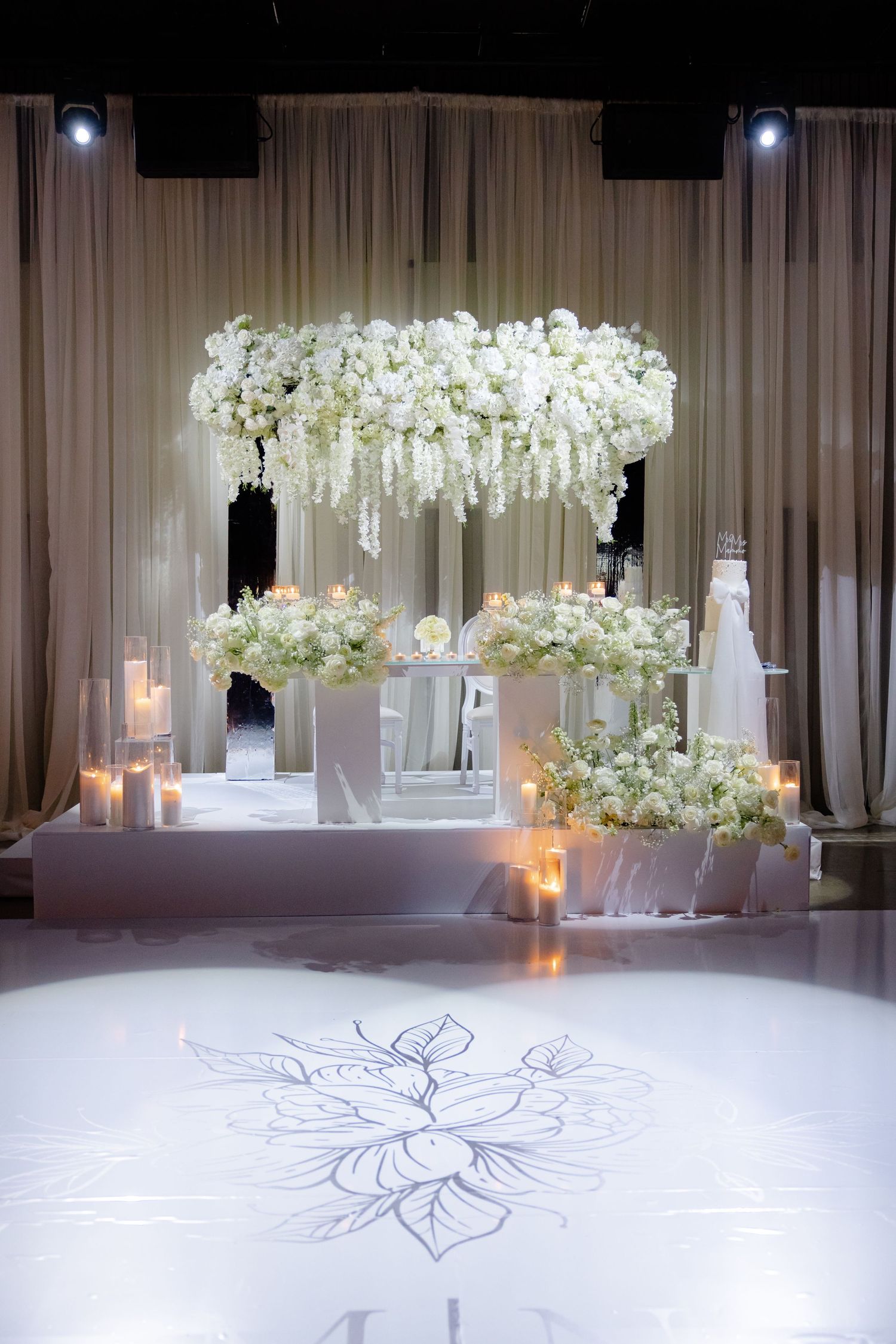 Luxurious wedding reception setup with white floral chandelier and candle lighting.