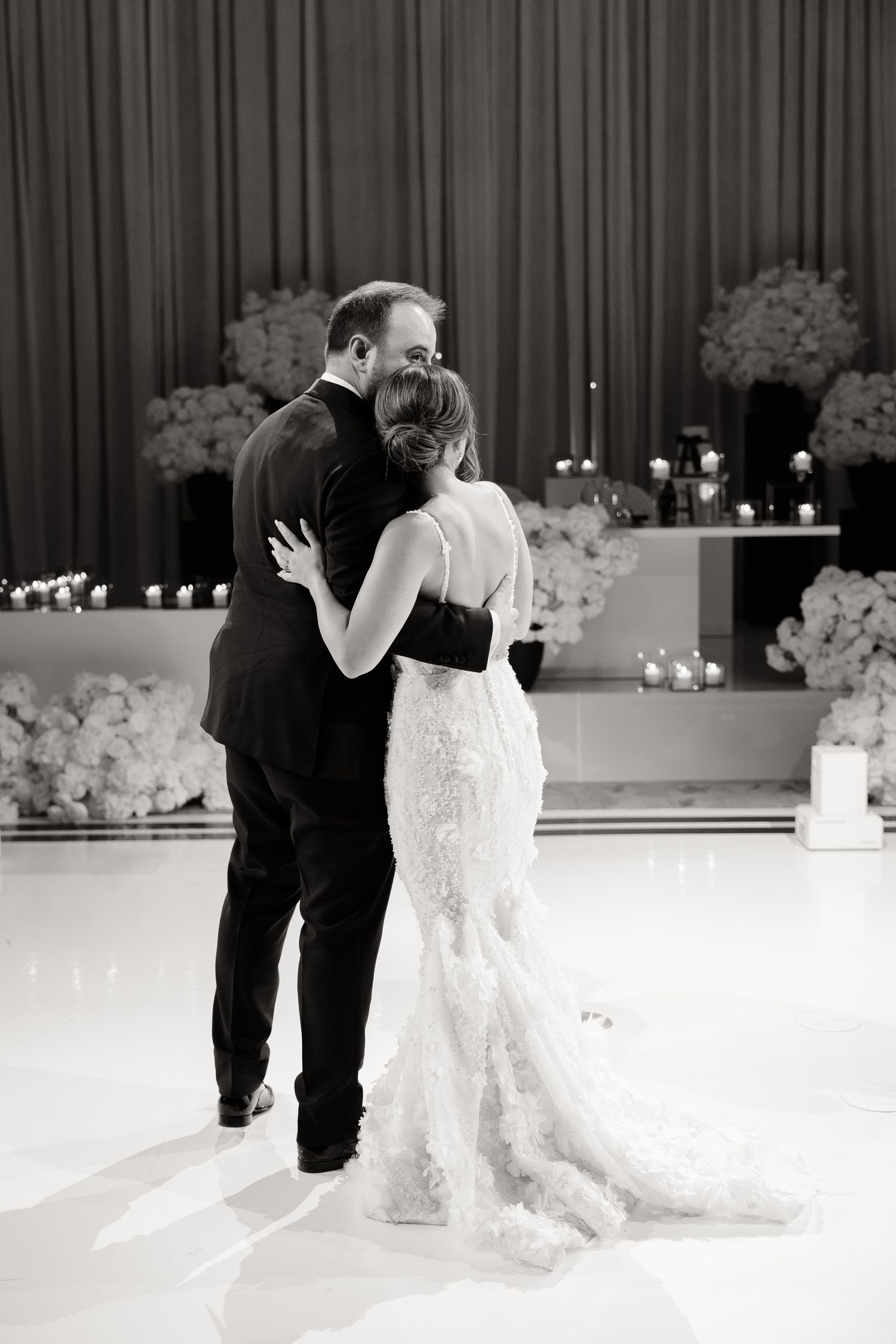 A romantic first dance sequence at a wedding reception with a white lace gown against a dark curtain backdrop.
