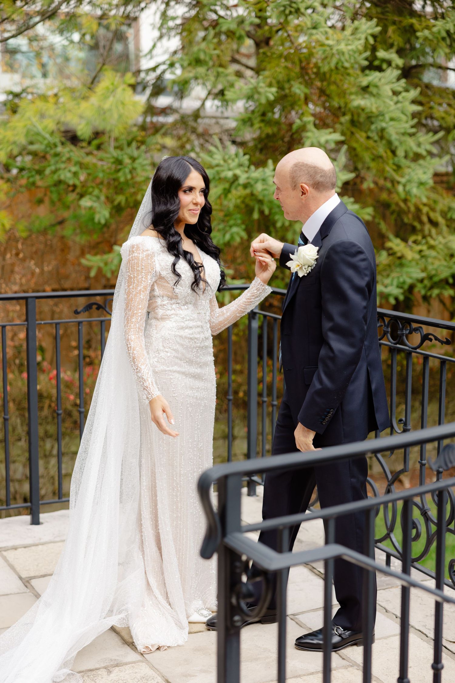 Wedding couple shares an intimate moment on a stone terrace with decorative iron railings.
