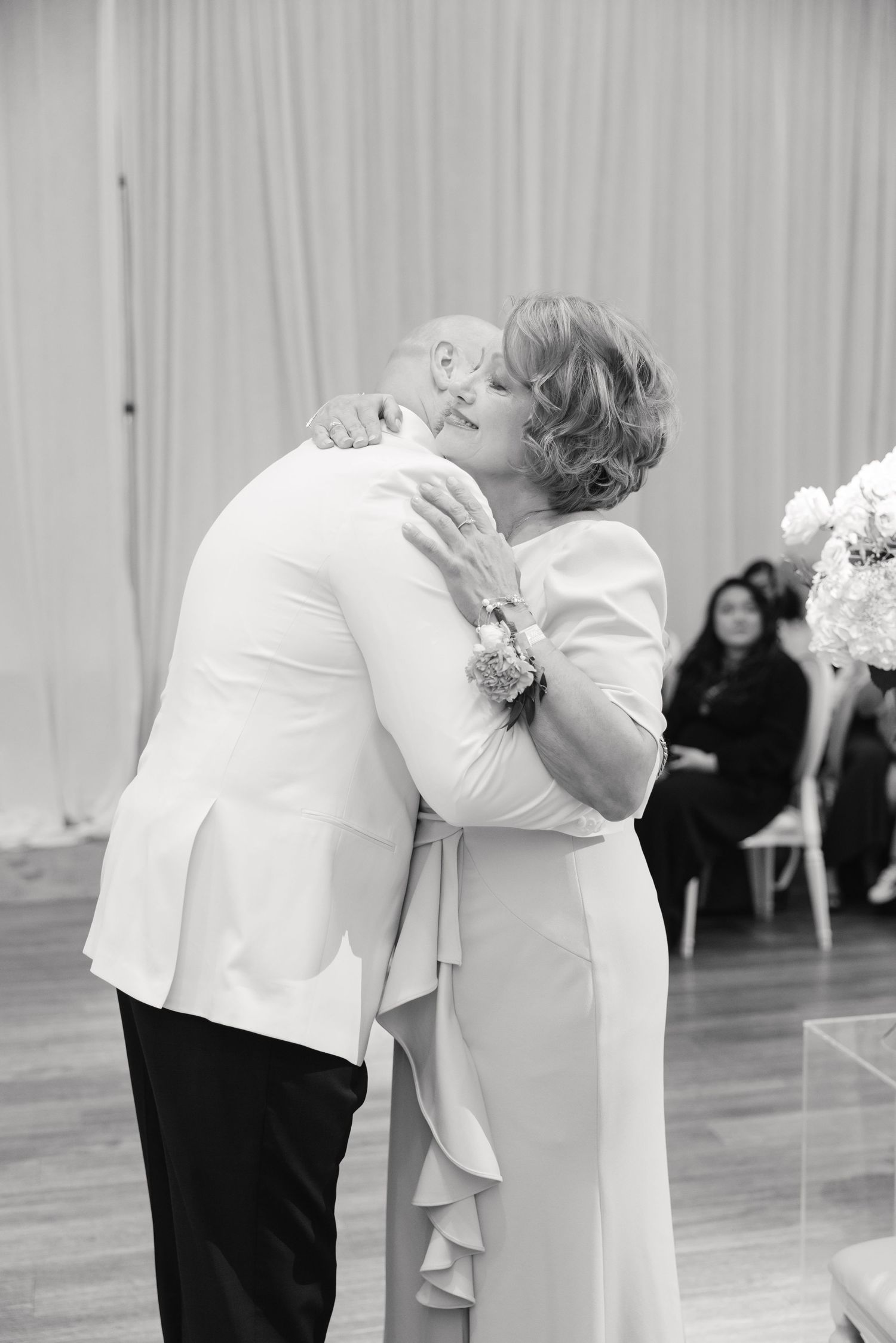 An emotional embrace shared during a wedding ceremony with guests seated in the background.