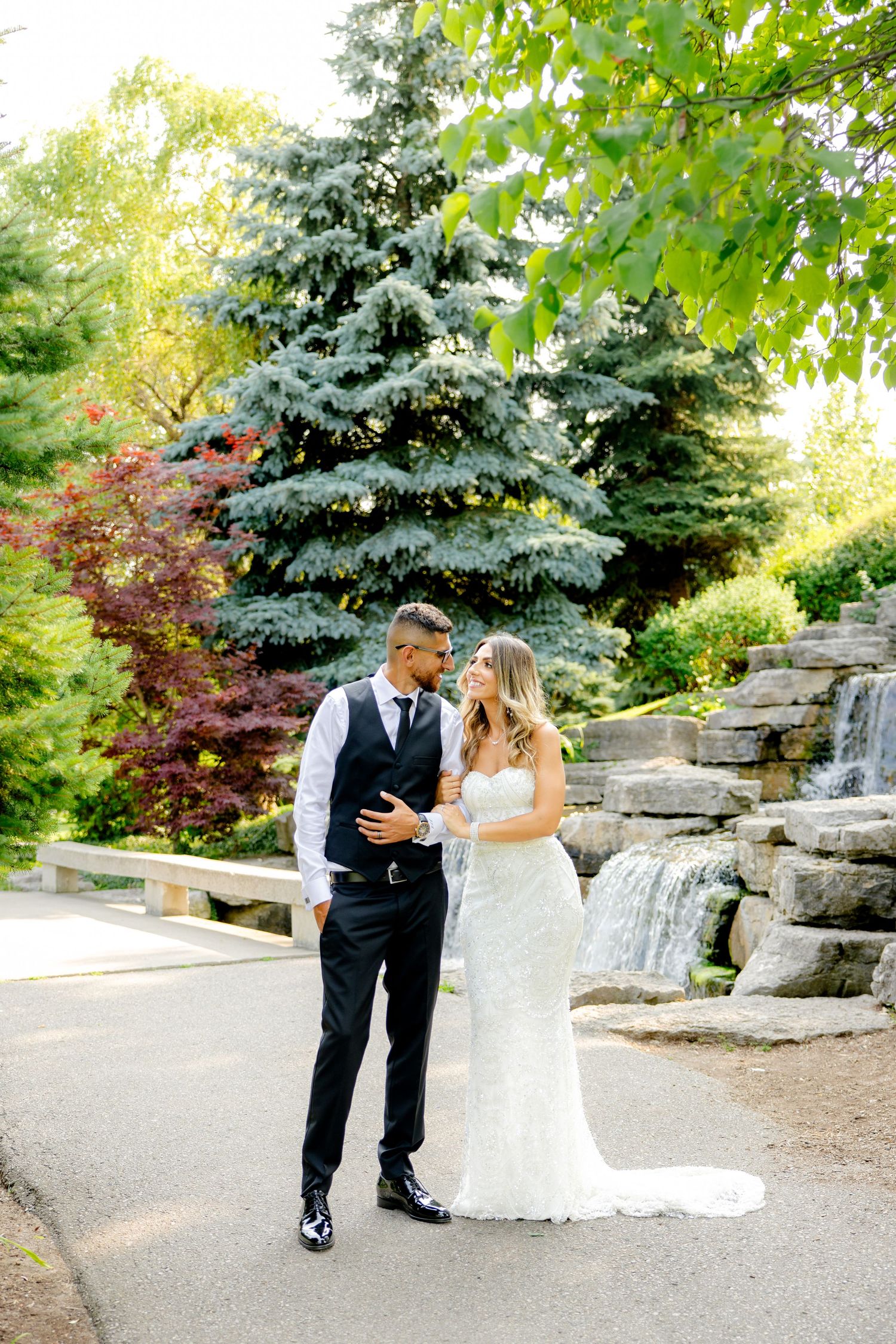 Joyful wedding photo with cascading stone waterfall and blue spruce trees.