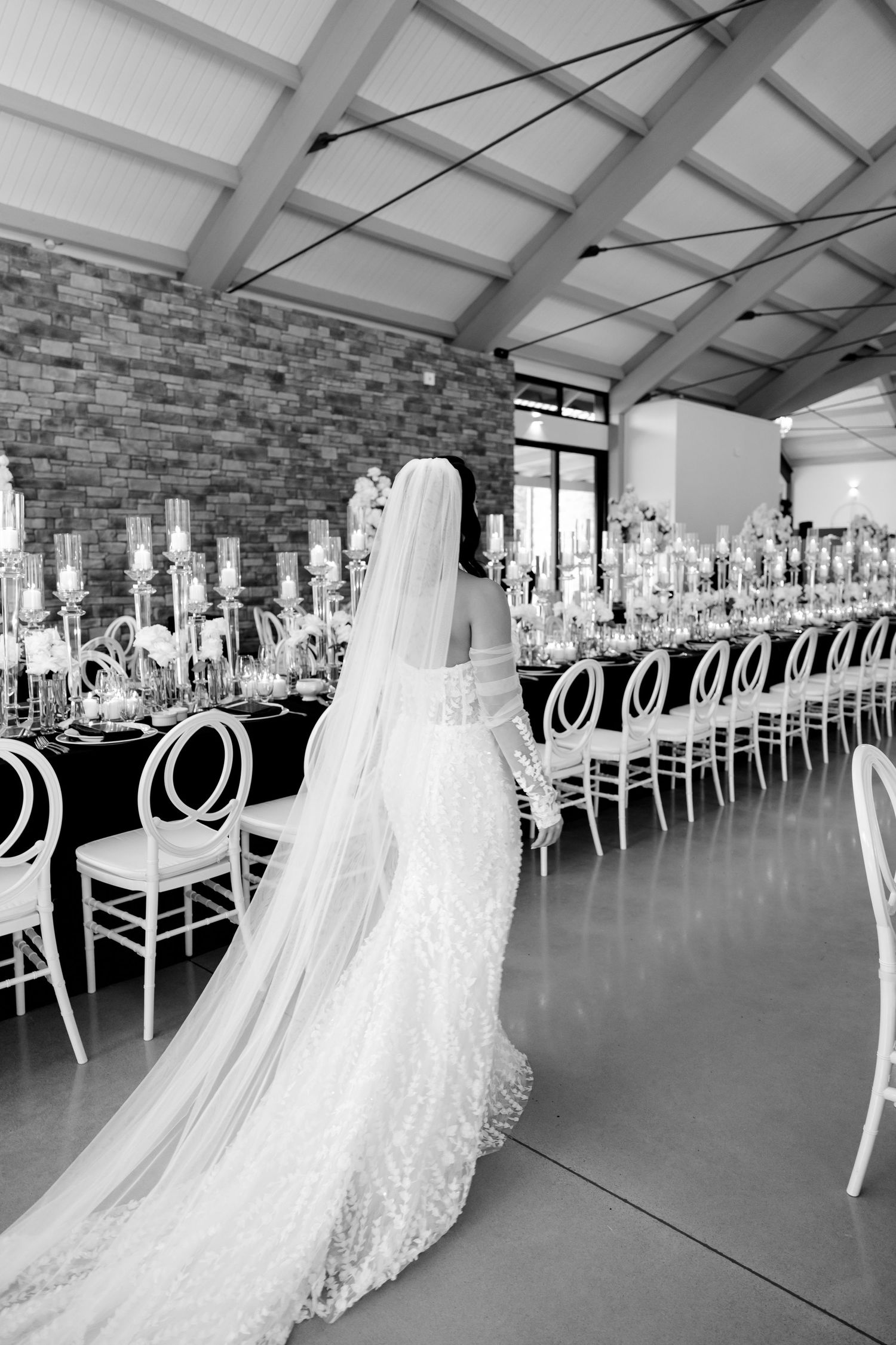 Long-trained wedding dress silhouette against elegant reception table setting.