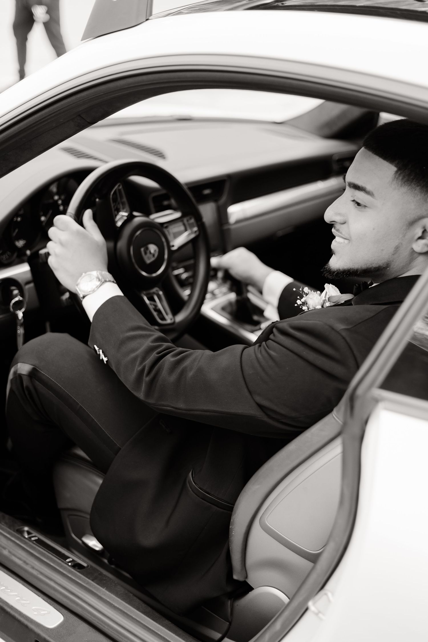 Side view of person in formal attire sitting in driver's seat of luxury vehicle.