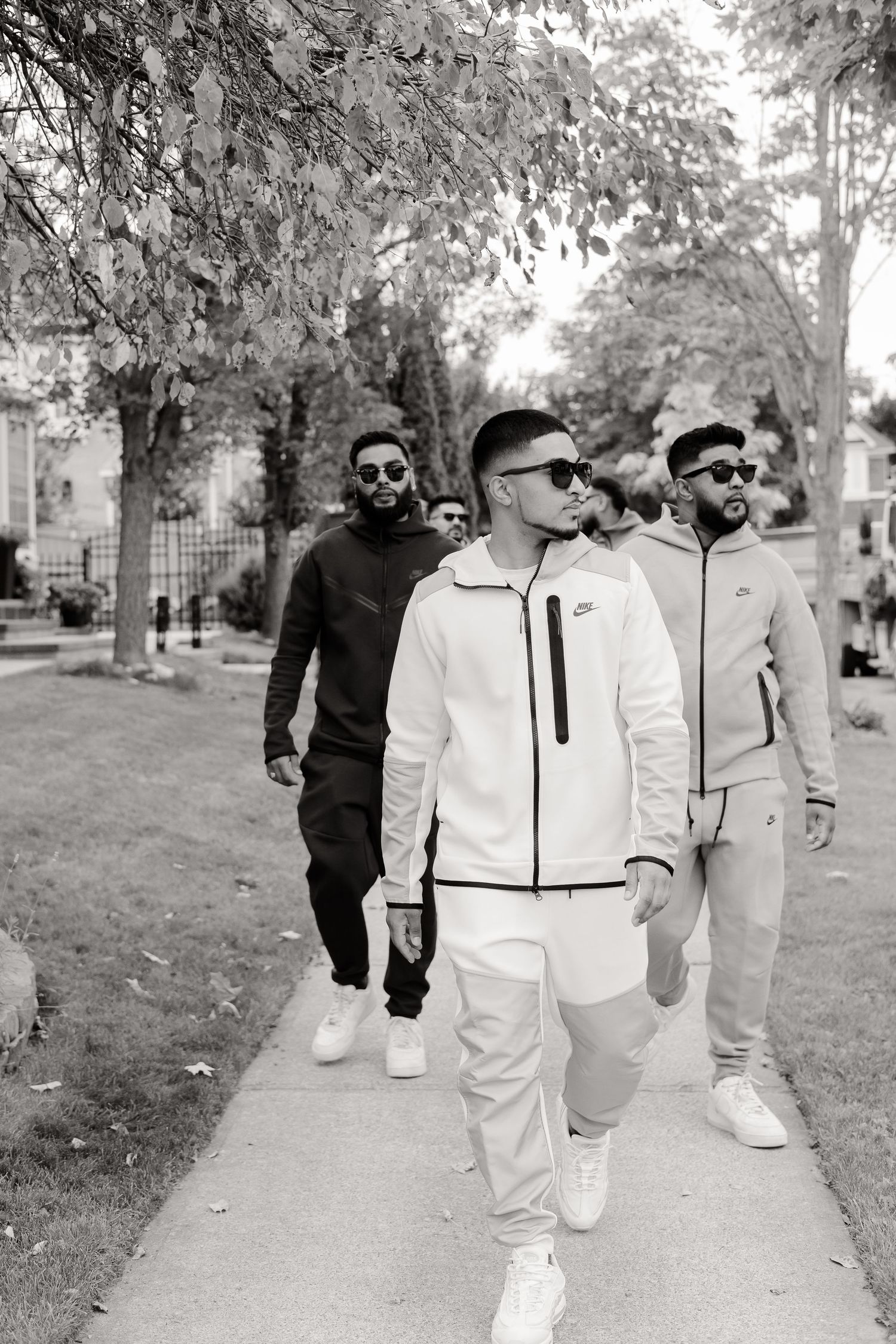A group walks along a tree-lined path in coordinated casual outfits.
