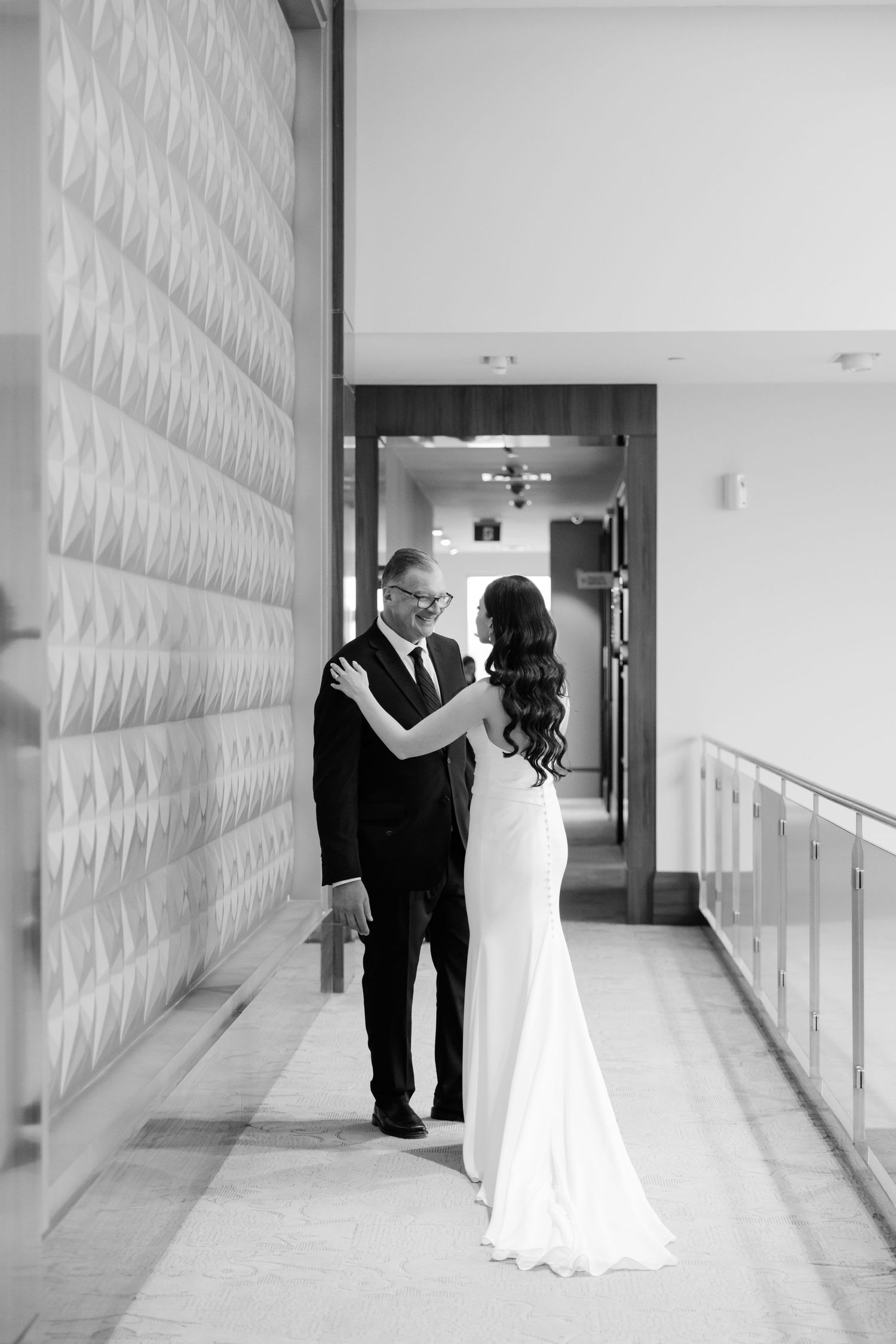 Black and white portrait of a couple embracing in an elegant corridor.