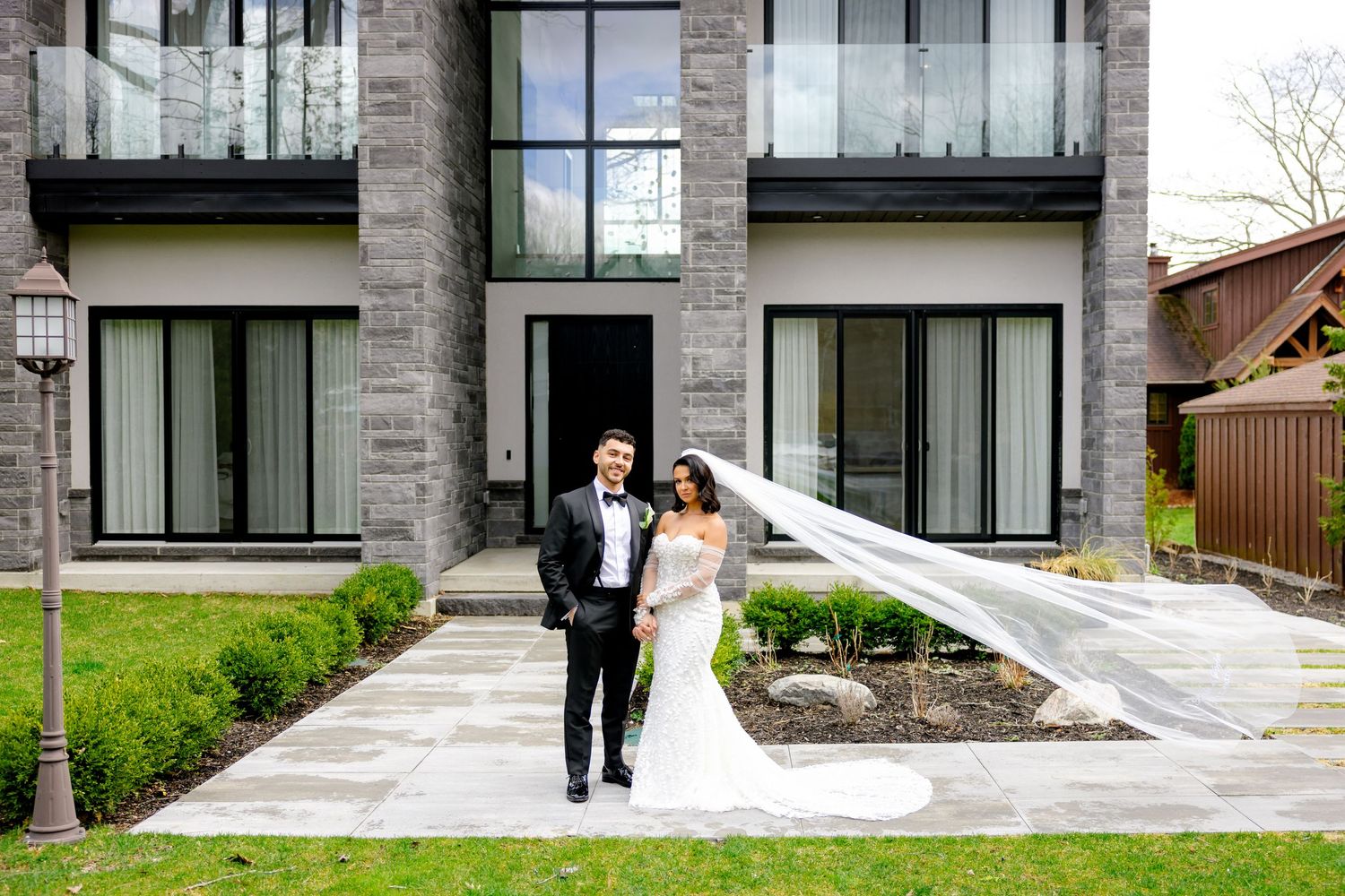 A couple walks along a modern building's walkway during their wedding photoshoot.