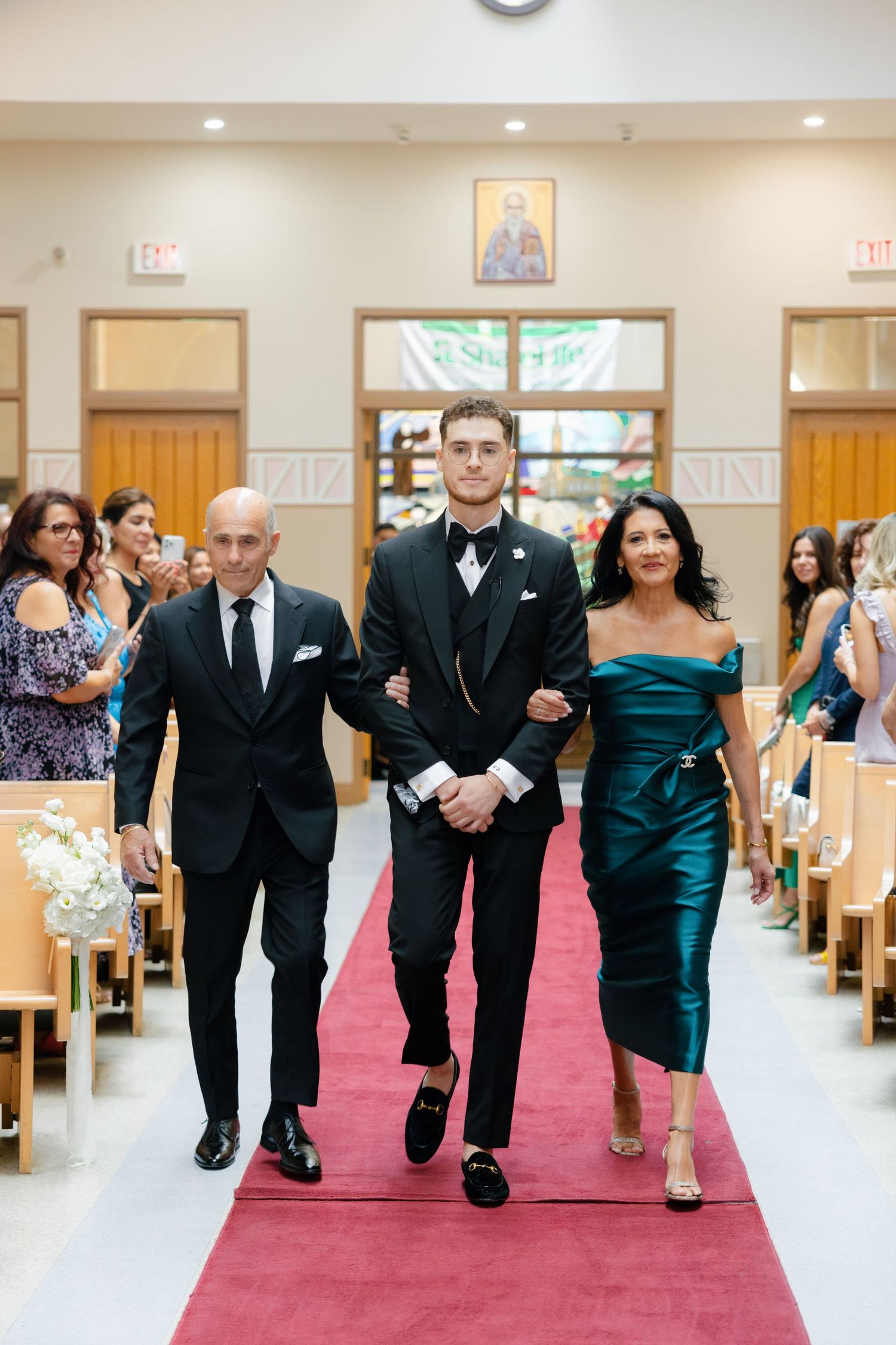 Wedding ceremony processional in a church with guests watching from wooden pews.