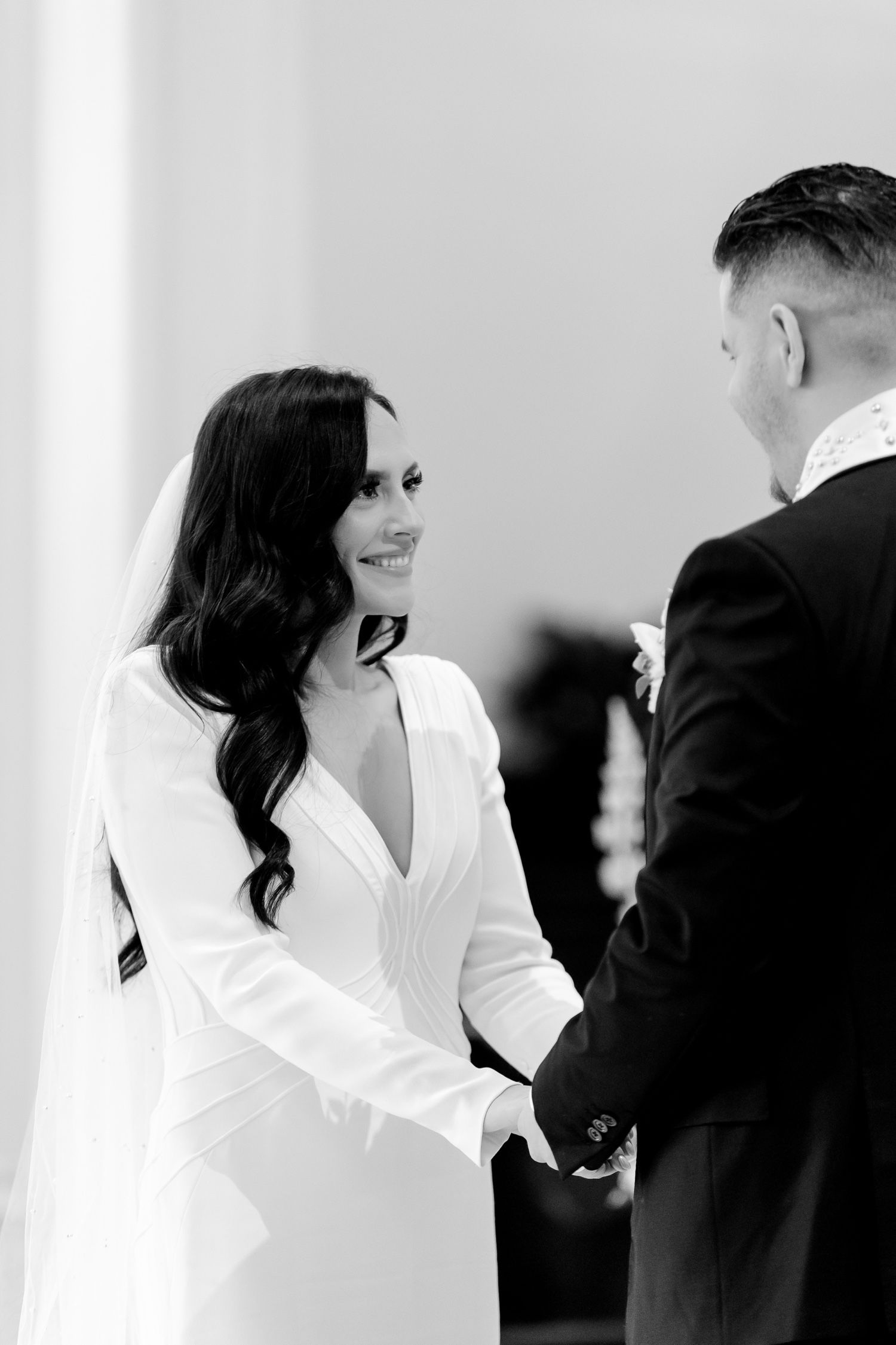 A black and white photograph capturing an intimate moment during a wedding ceremony.