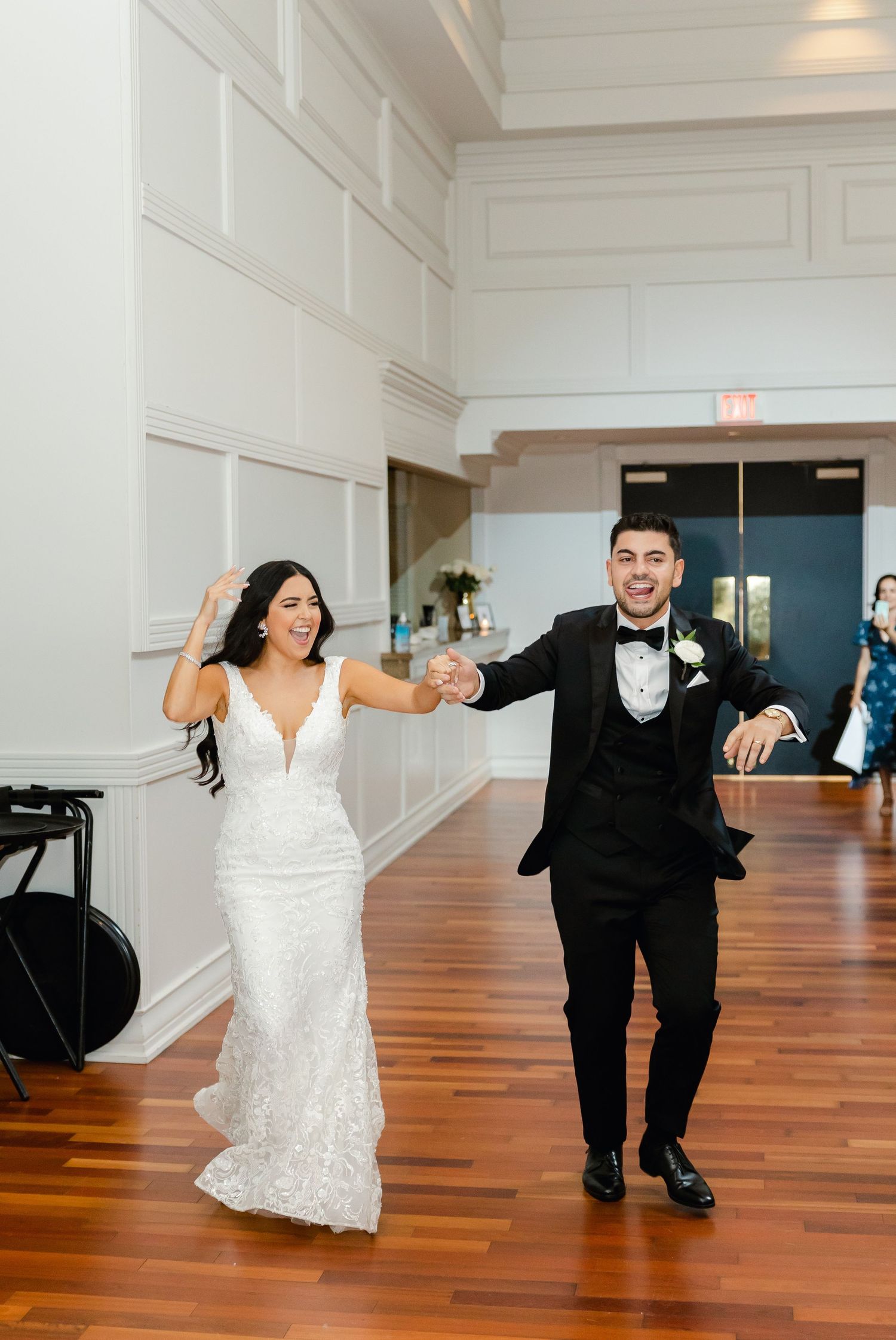 Joyful celebration in an elegant white-walled venue with wooden floors.