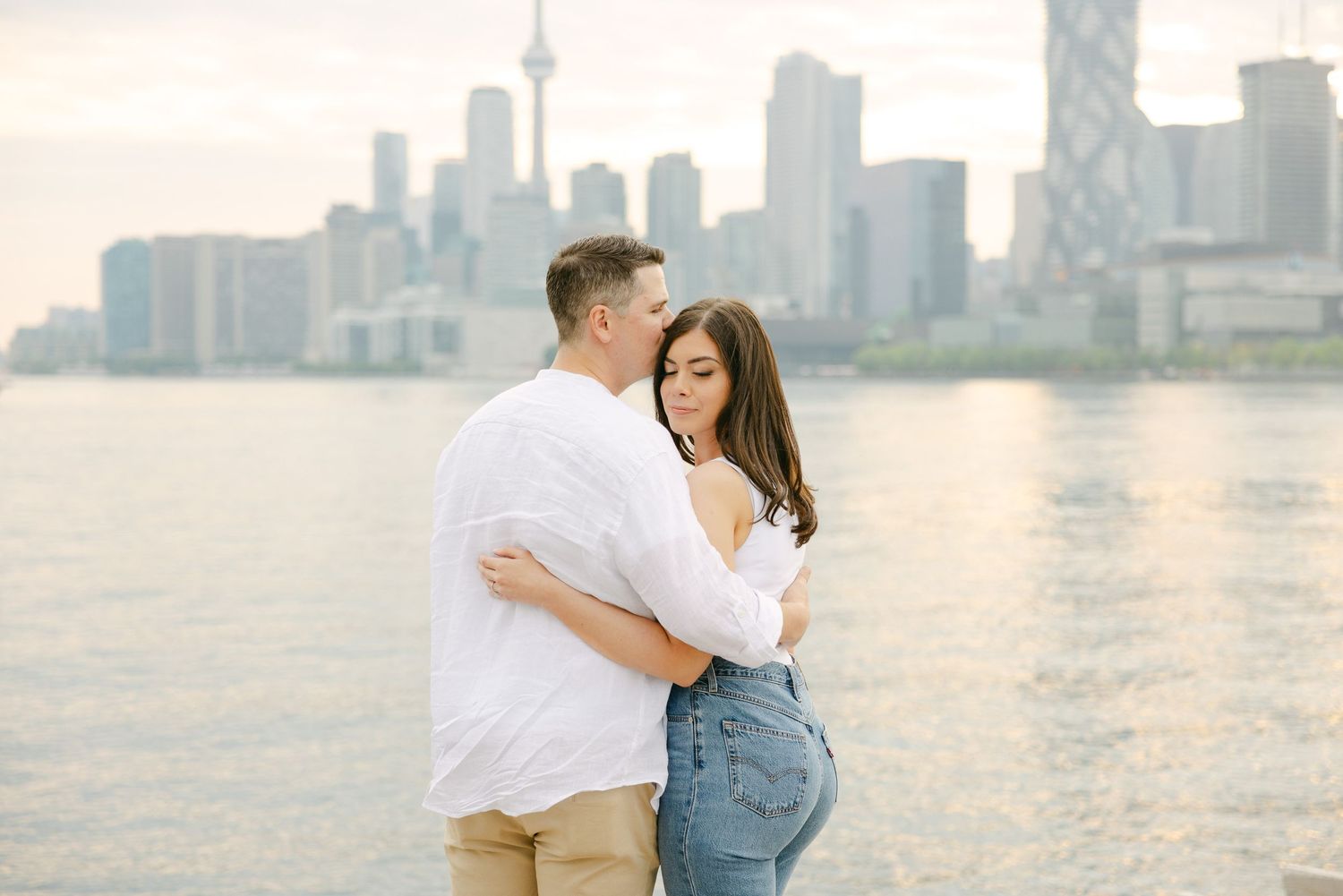 A tender embrace captured against Toronto's waterfront skyline during golden hour.