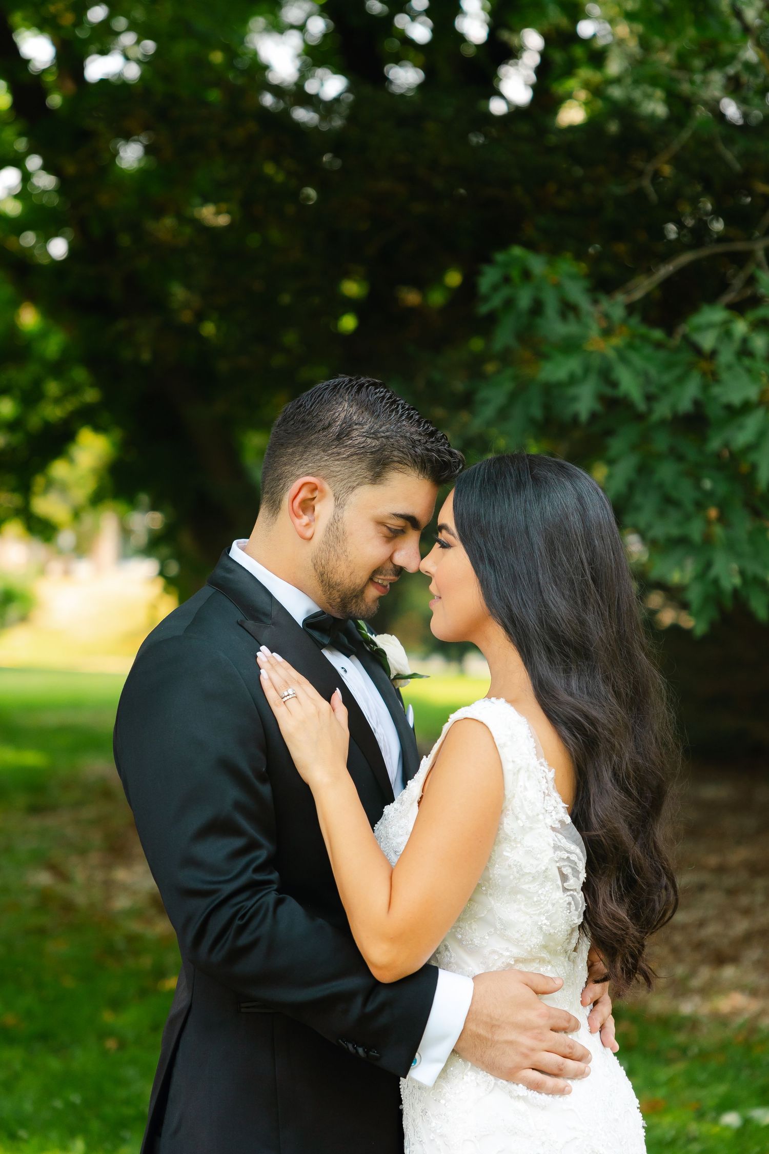 An intimate wedding portrait of a couple embracing in a sunlit garden.