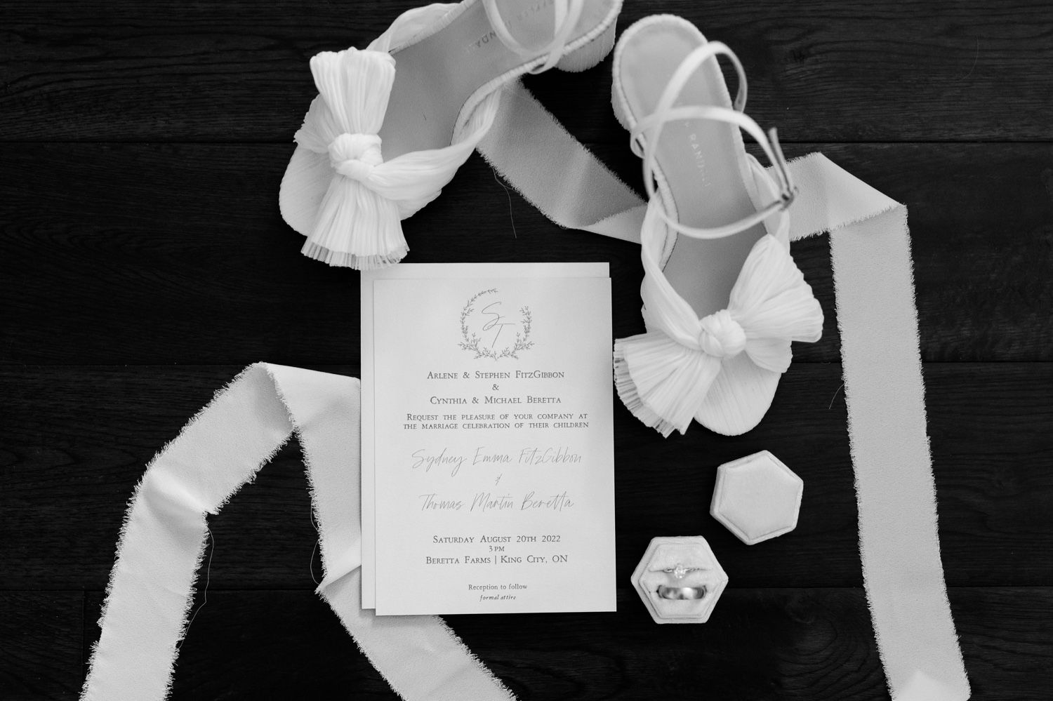 Black and white photo of wedding invitation with delicate white ribbons and geometric accents.