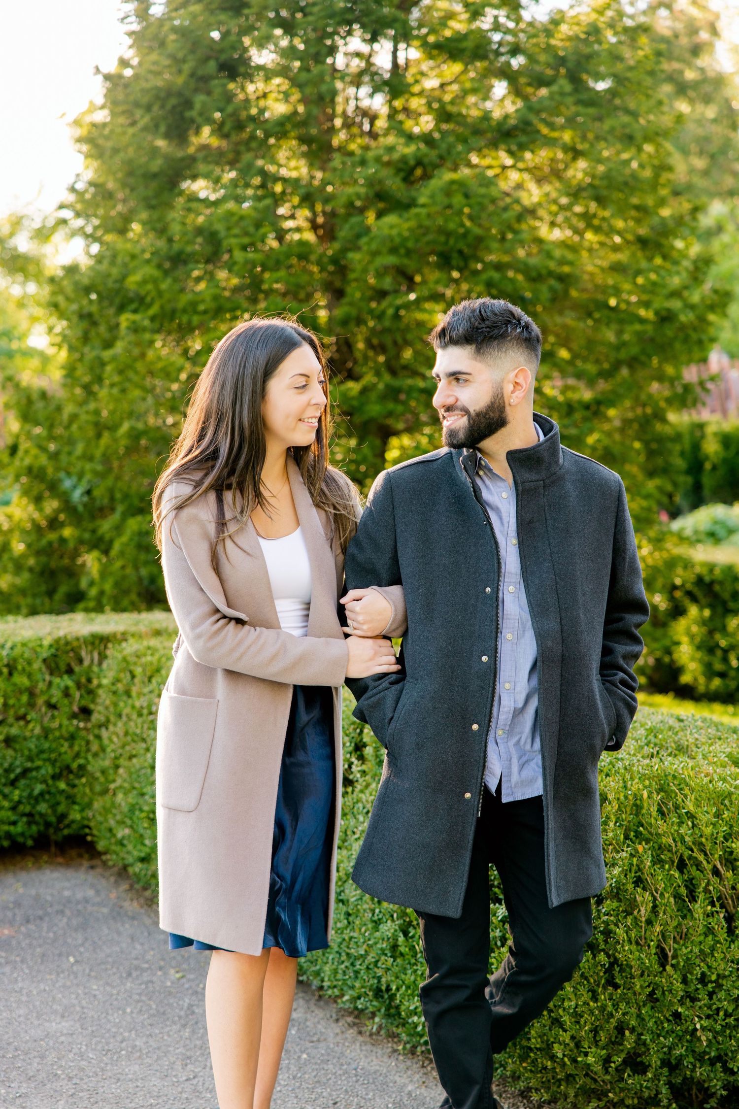 Couple taking a romantic stroll through a garden path during golden hour.