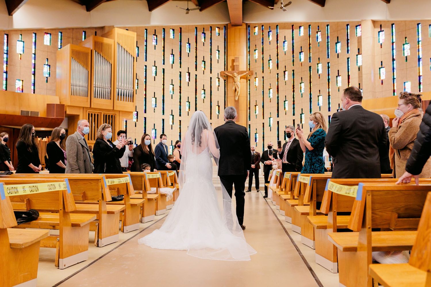 Wedding ceremony in progress with decorative vertical lights and wooden pews in church sanctuary.