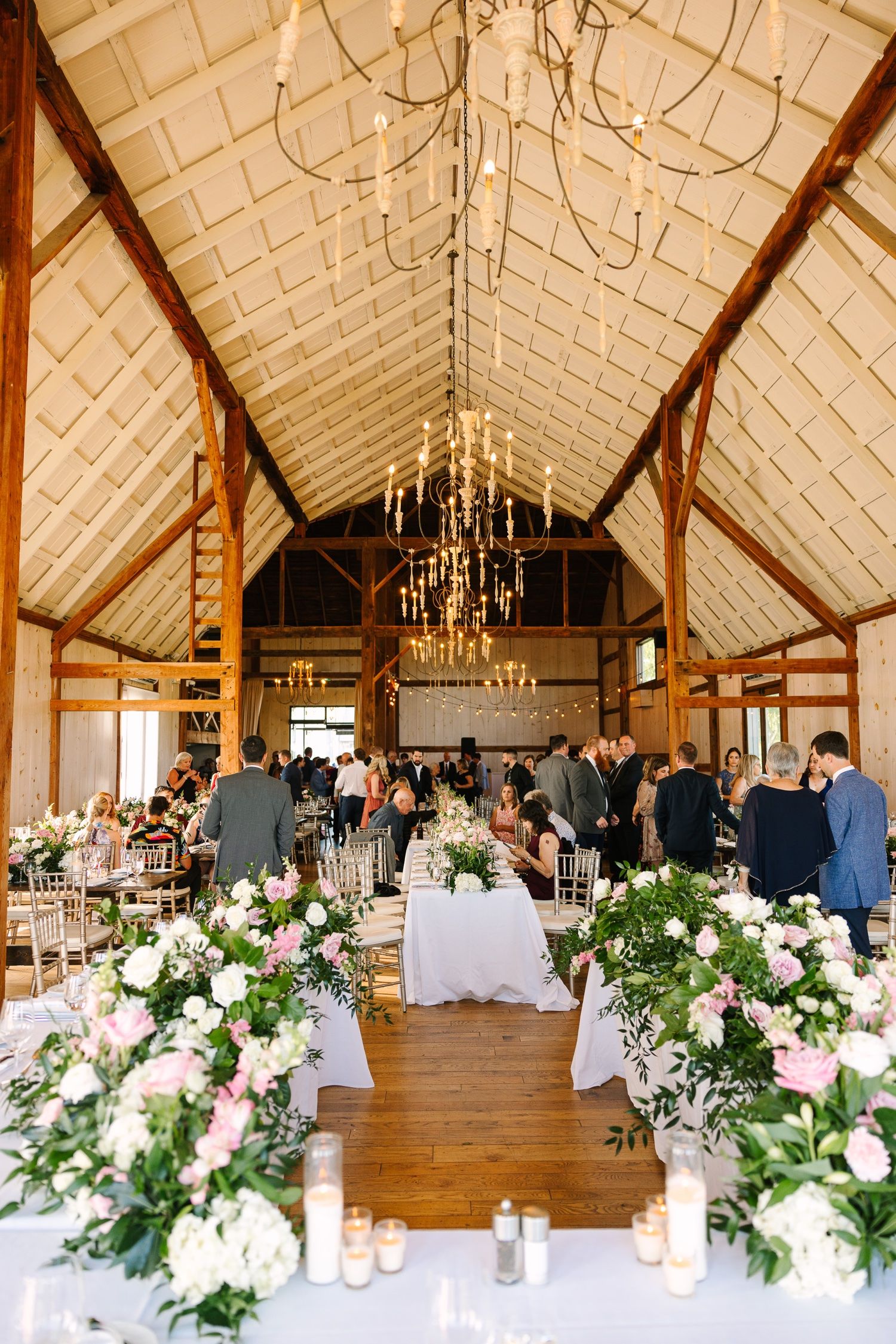Rustic barn wedding venue with cathedral ceiling and romantic floral aisle decorations.