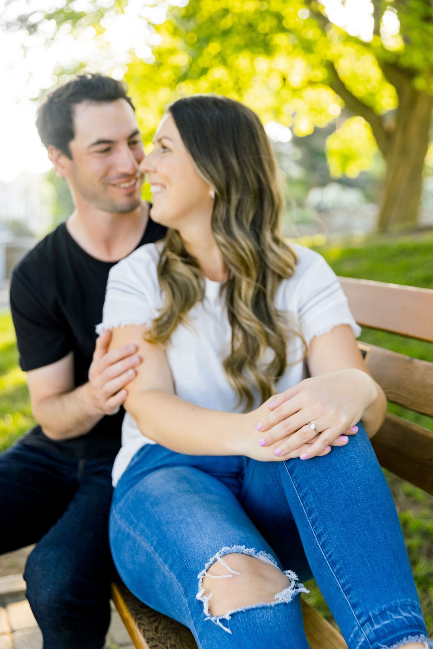 A couple shares intimate moments while sitting together on a park bench.
