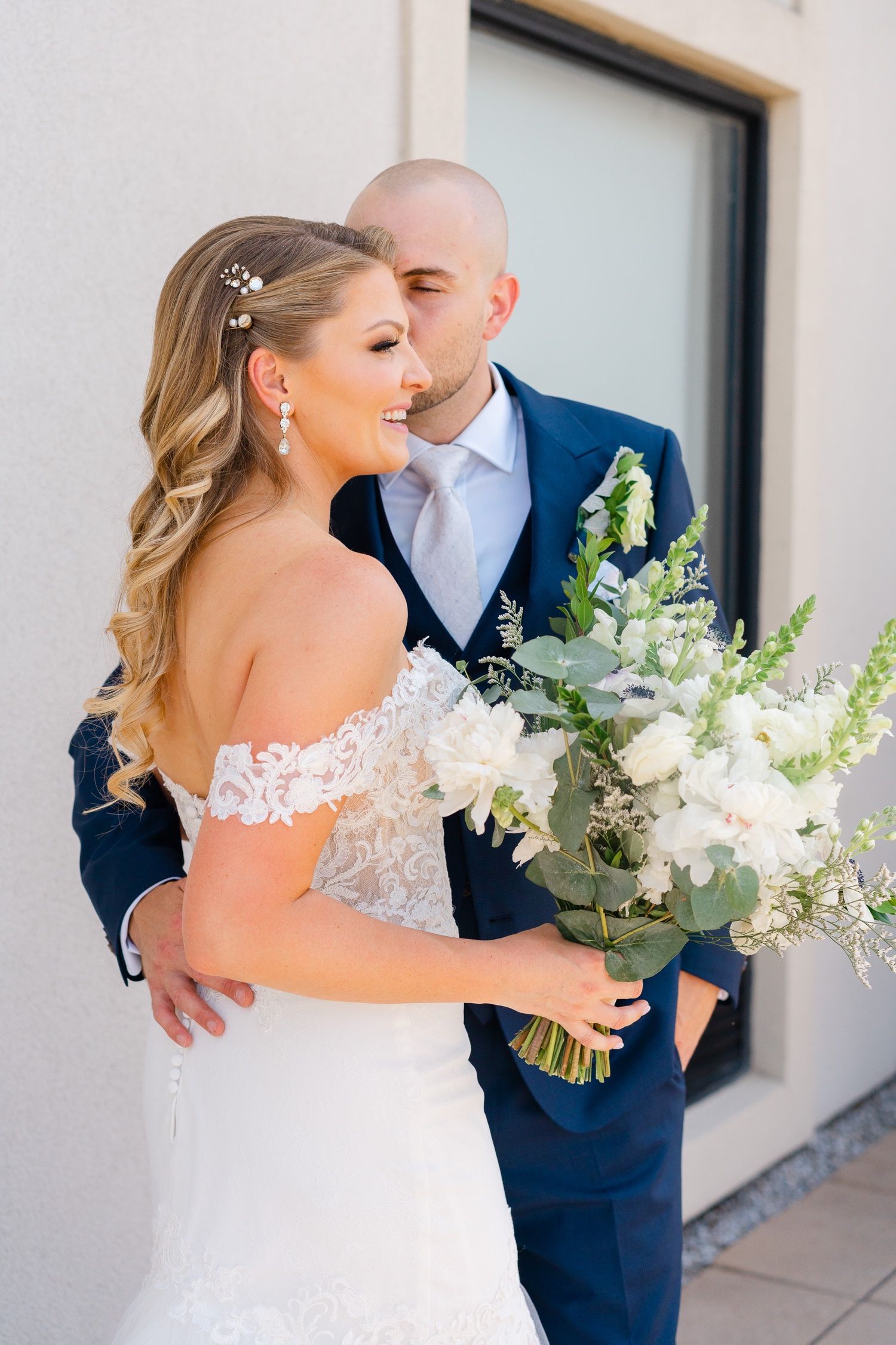 Intimate wedding portrait with beautiful white bouquet and off-shoulder lace gown detail.