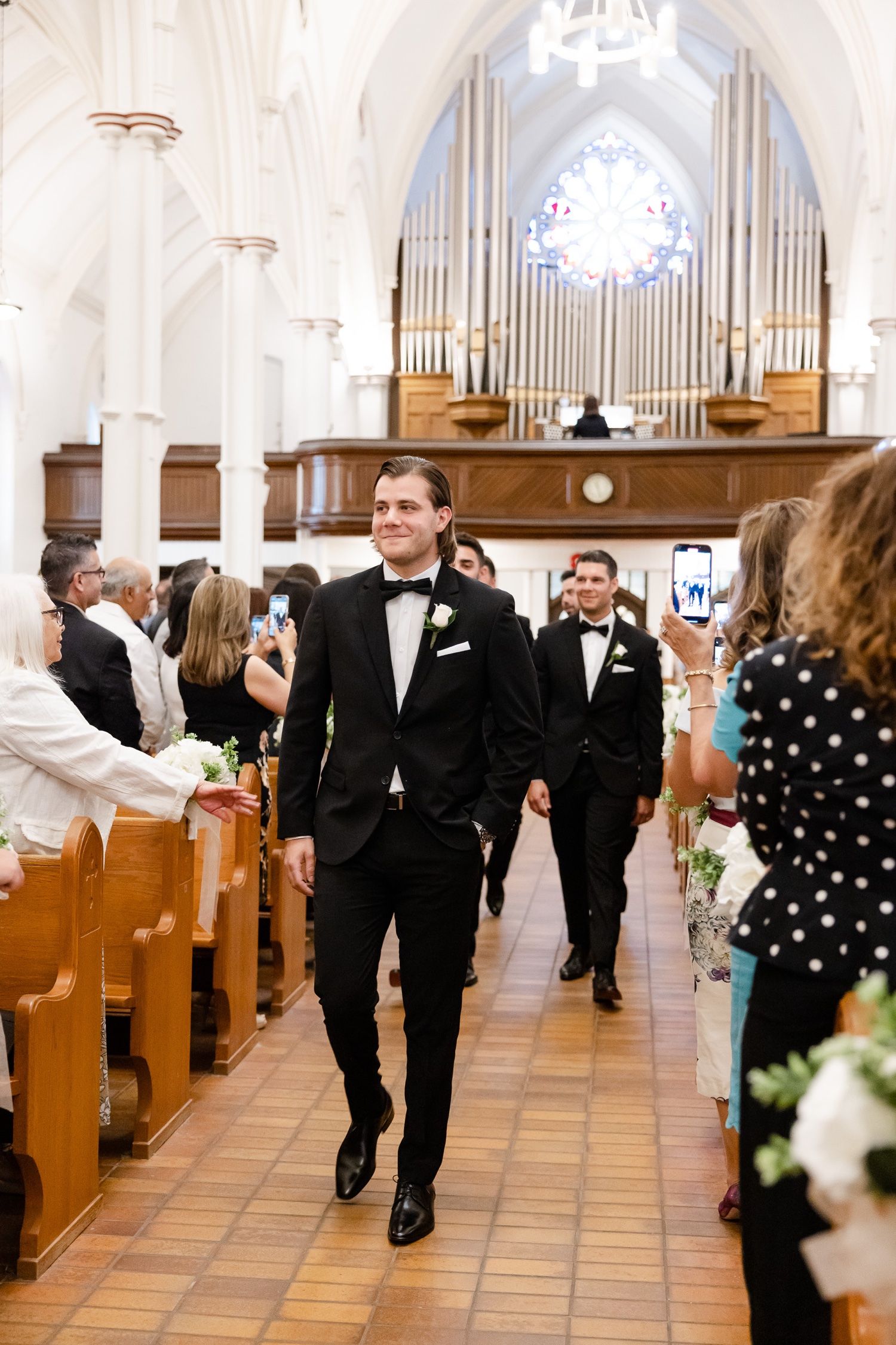 Elegant church wedding processional with wooden pews and grand pipe organ in background.
