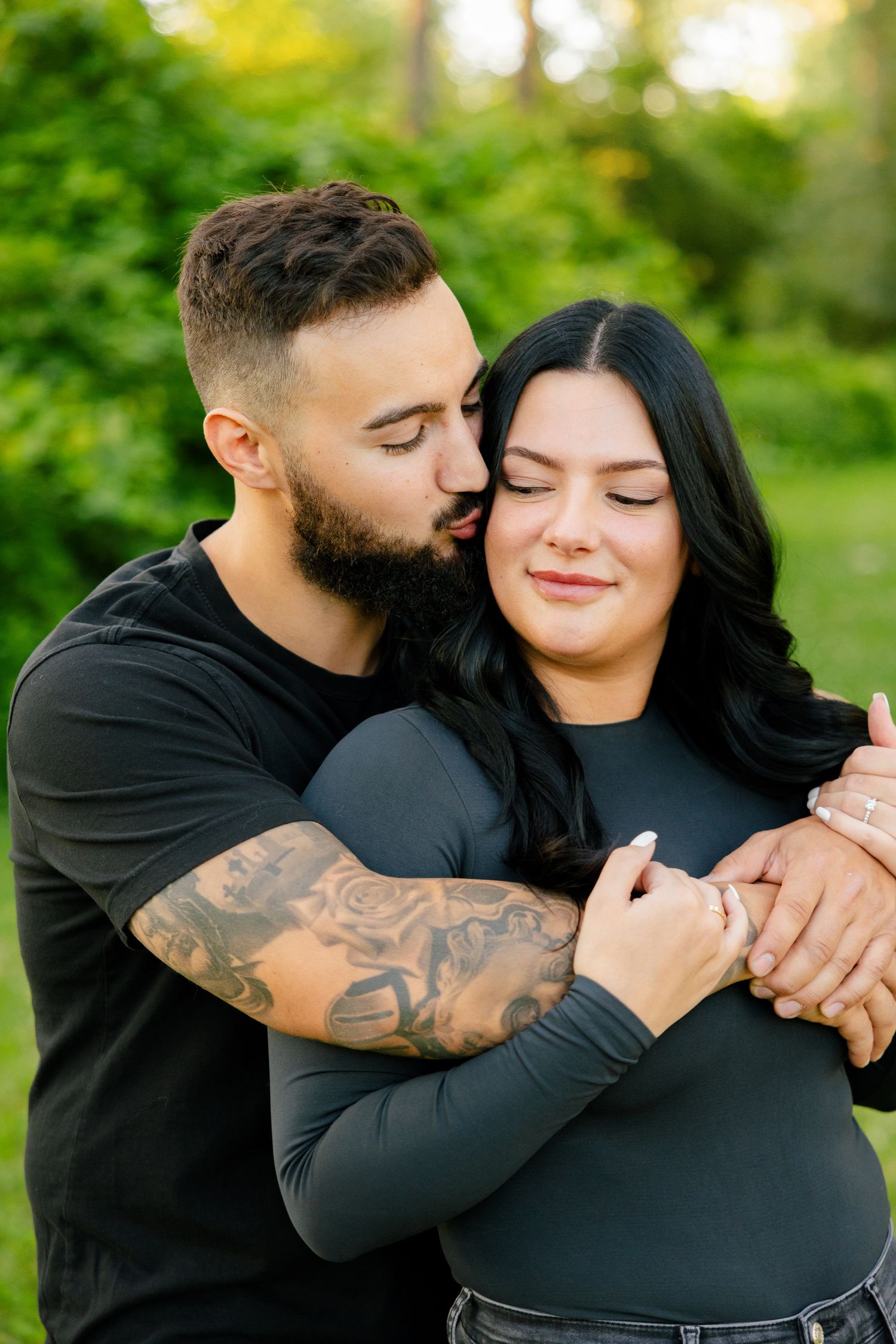 Intimate moment captured between couple as they embrace in sunny outdoor setting.