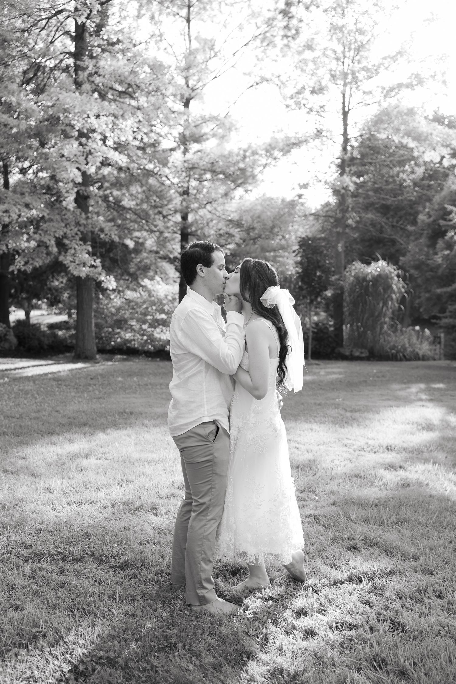 Black and white portrait of a couple in a dreamy garden setting with soft natural light.
