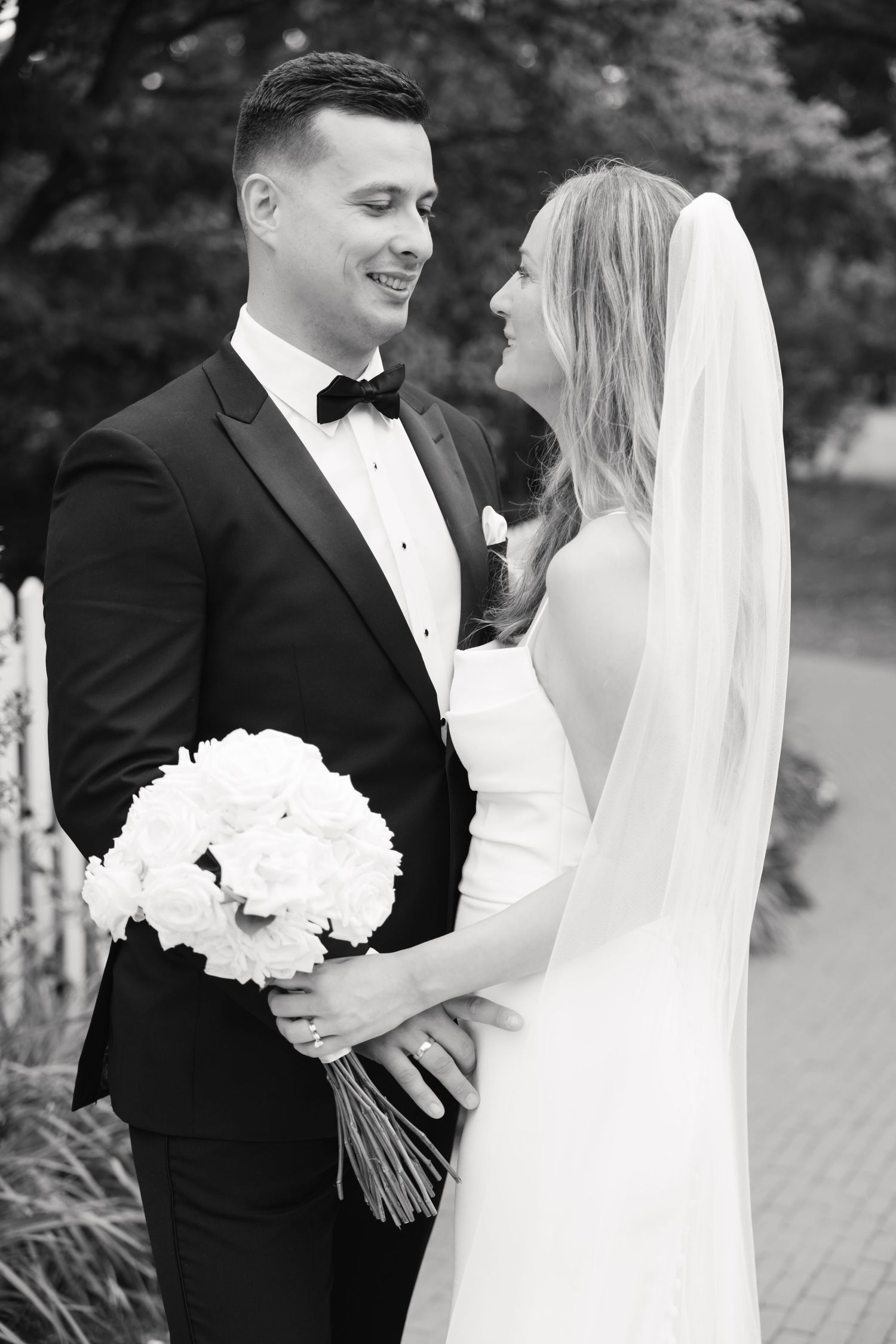 A black and white portrait of a happy wedding couple with white bouquet.