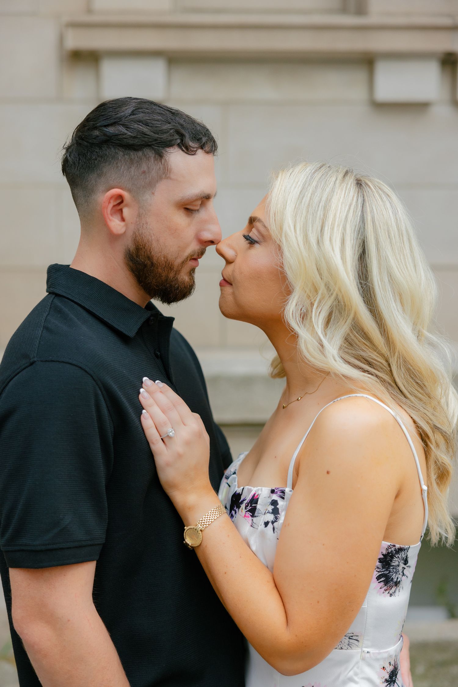 Romantic couple sharing tender moment against stone building exterior.