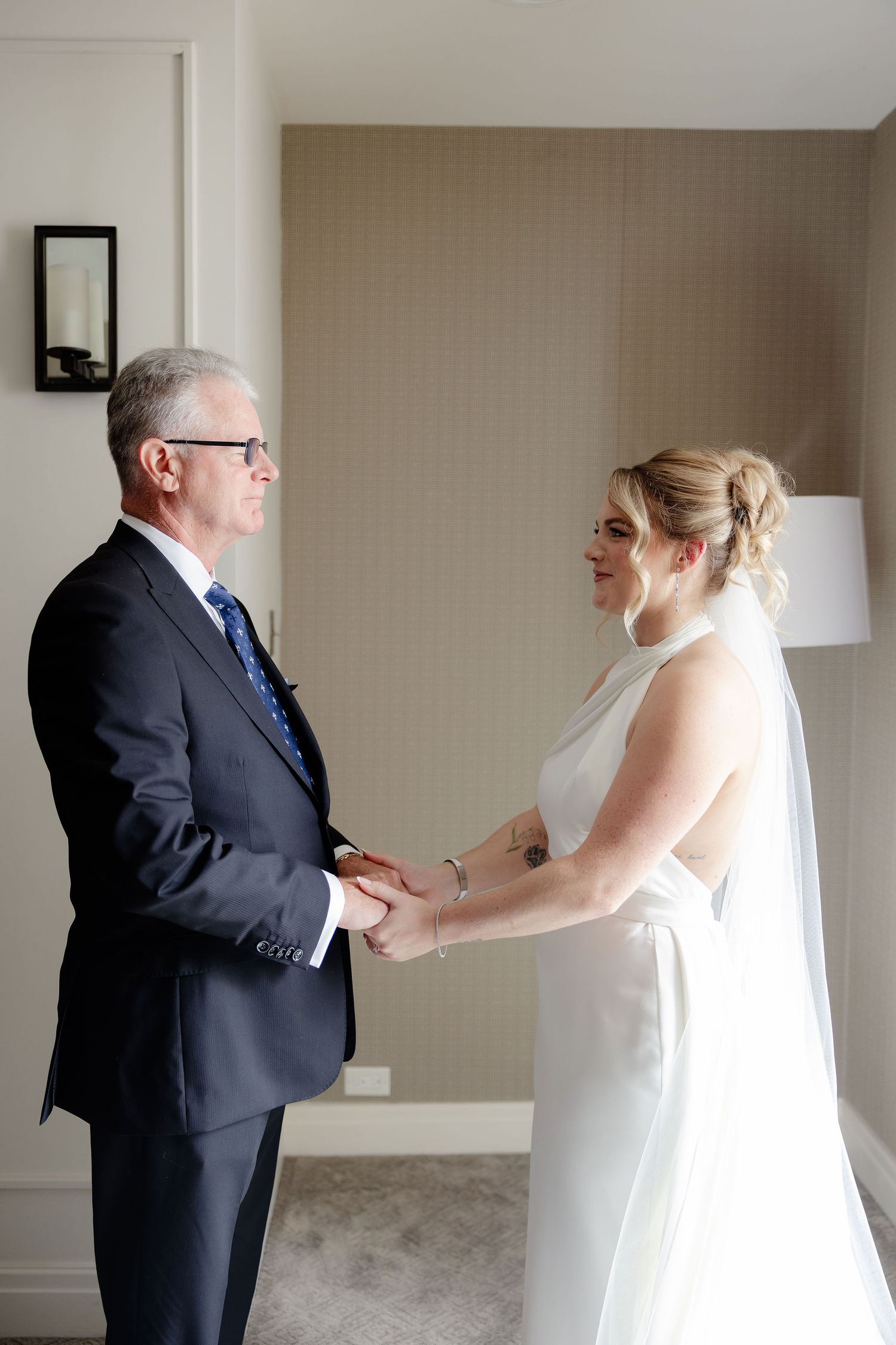 A series of candid moments showing a bride and her father sharing an emotional first look in a neutral-toned room.