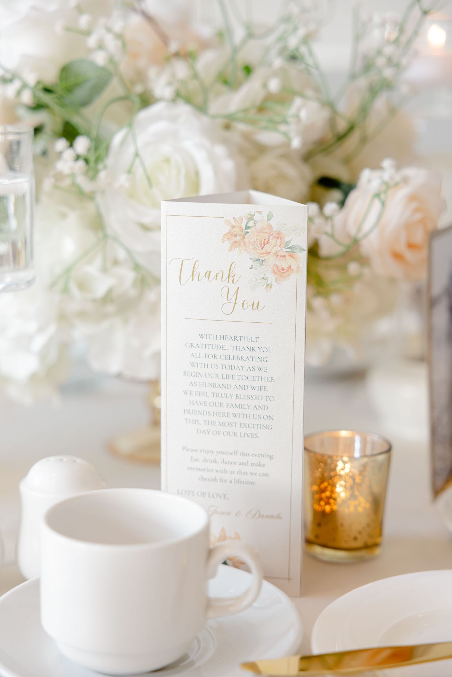 Elegant white and blush floral arrangements on wedding reception table.
