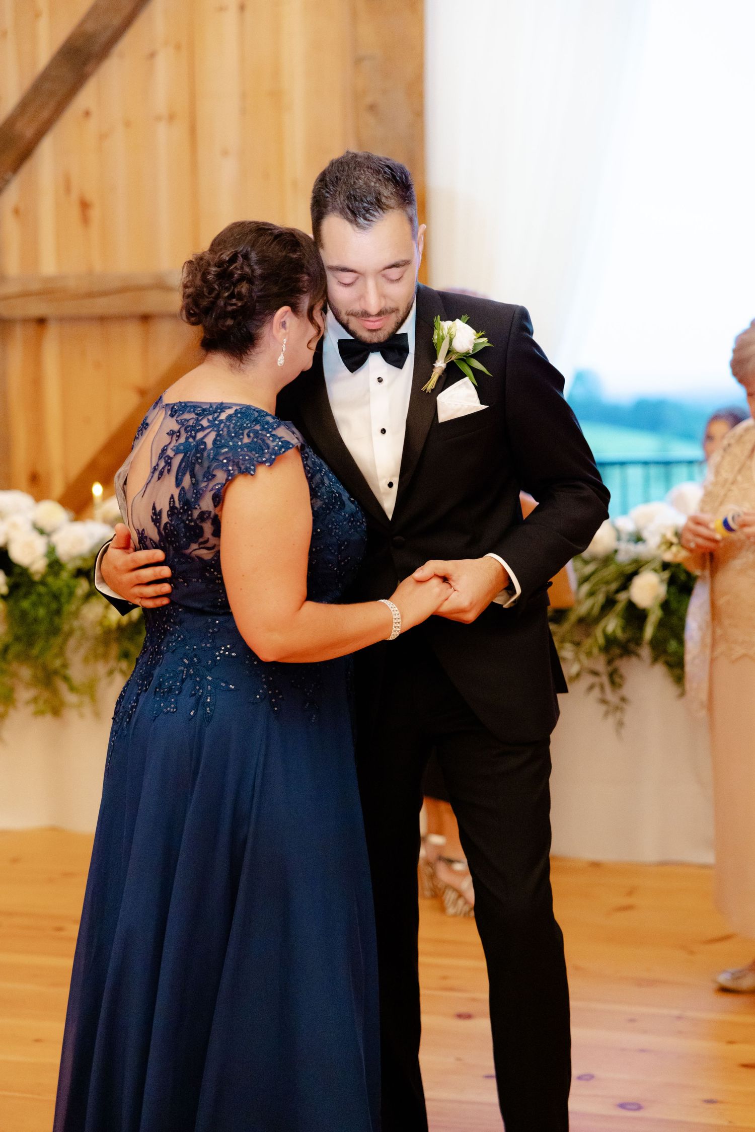 A couple share an intimate dance moment in a rustic barn setting with wooden walls.
