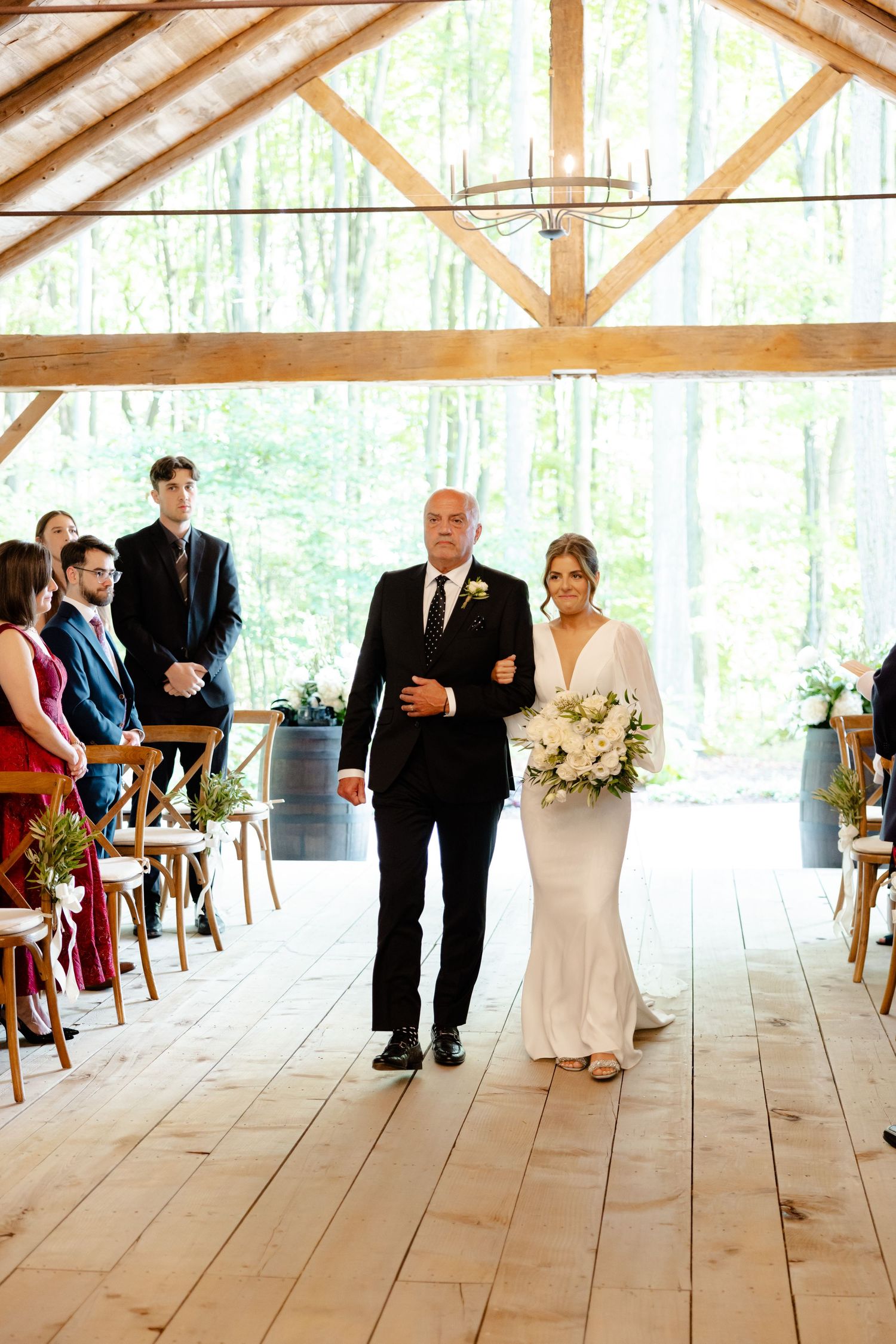 A wedding ceremony taking place in a beautiful wooden barn with natural light streaming in.