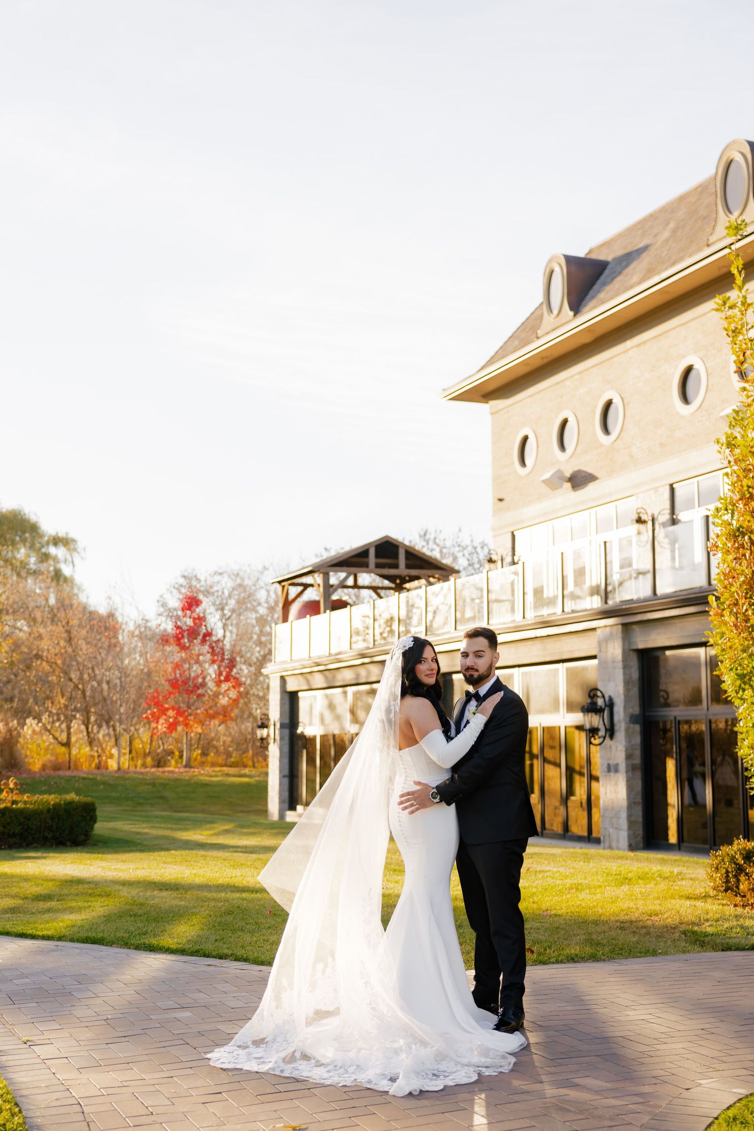Elegant wedding portrait in golden afternoon light by stone building.