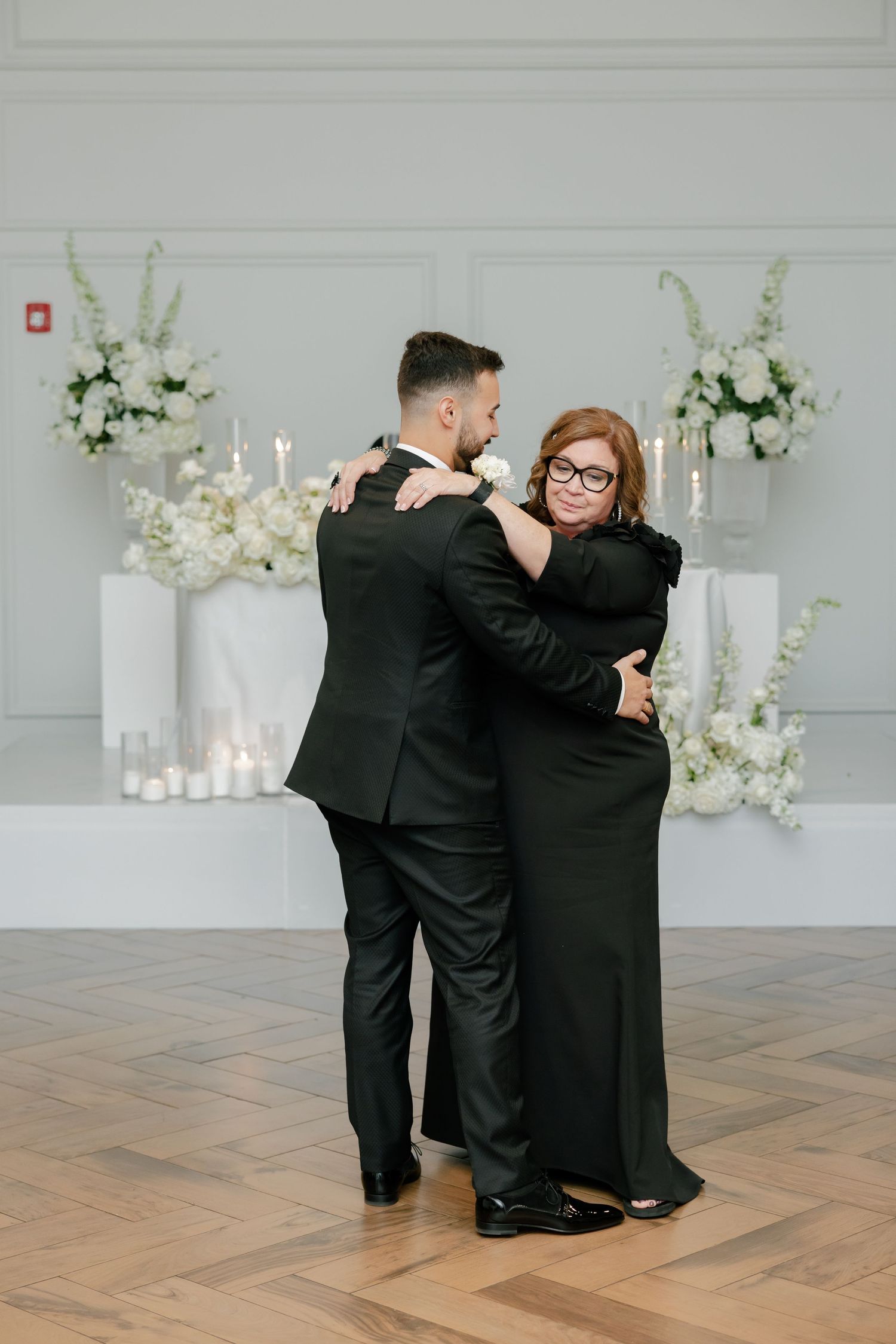 A couple dancing at a wedding reception with elegant white floral decorations in the background.