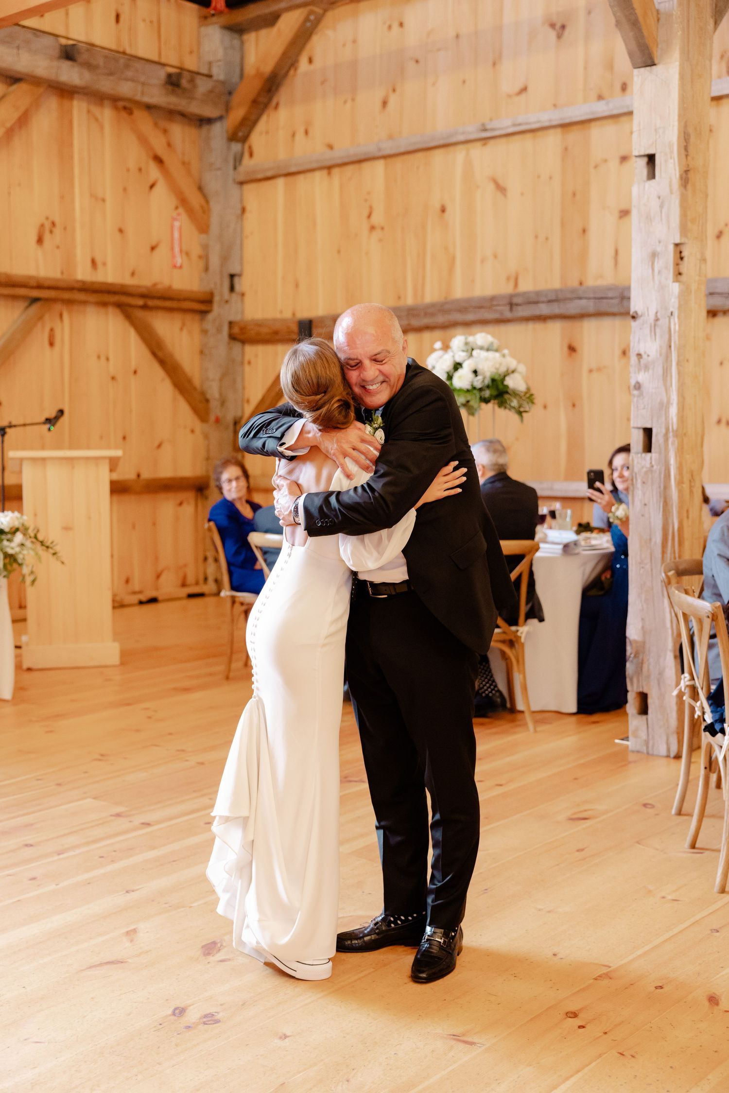 A couple embracing during their wedding dance in a rustic wooden barn setting.