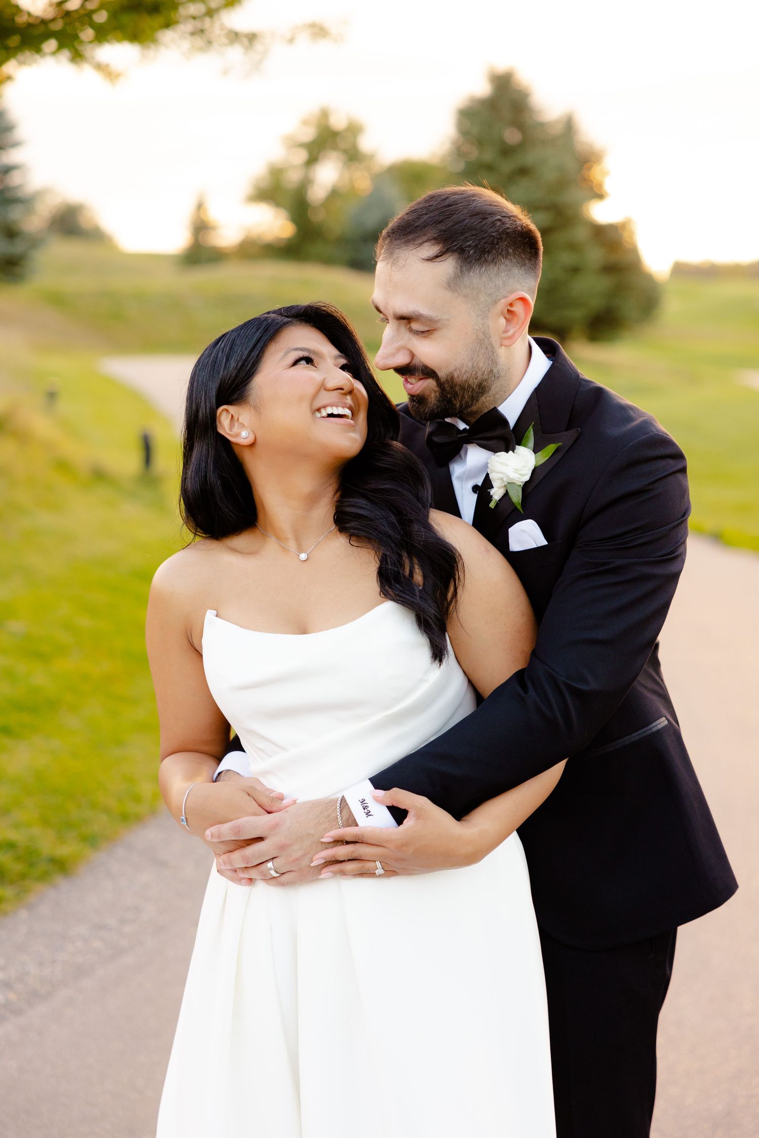 Happy couple shares intimate moment on wedding day at sunset on outdoor path.