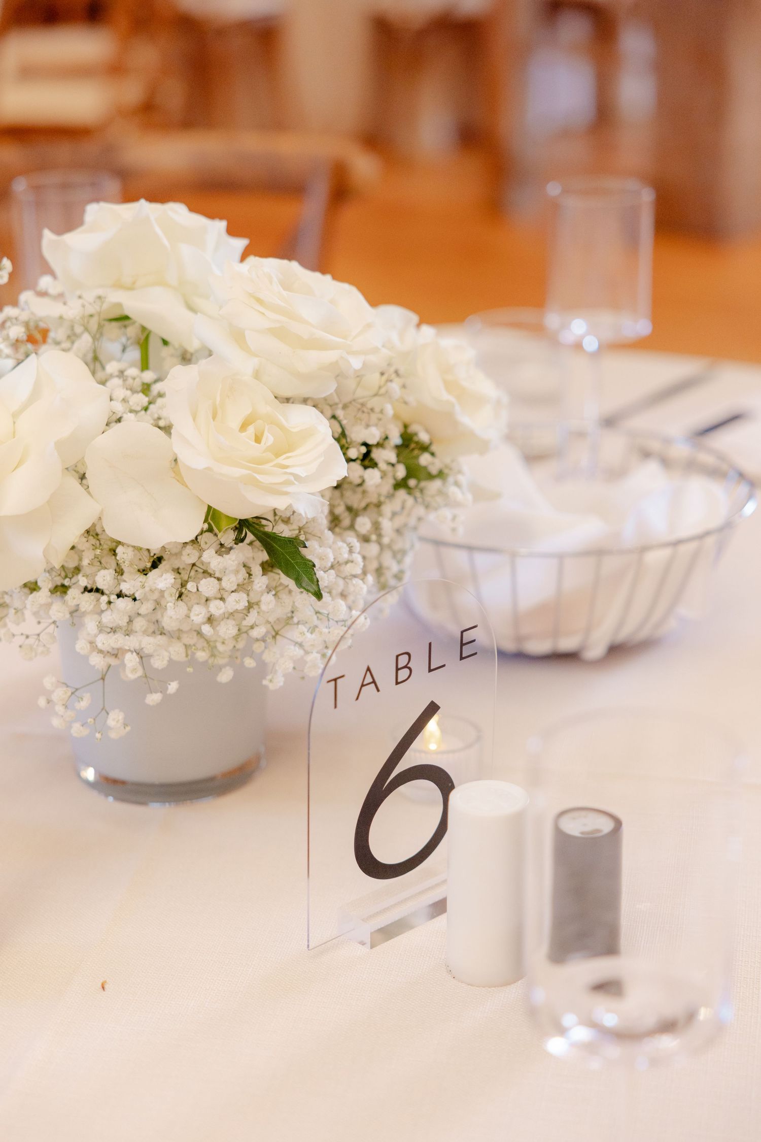 Wedding reception table setting with white floral centerpiece and table number six.