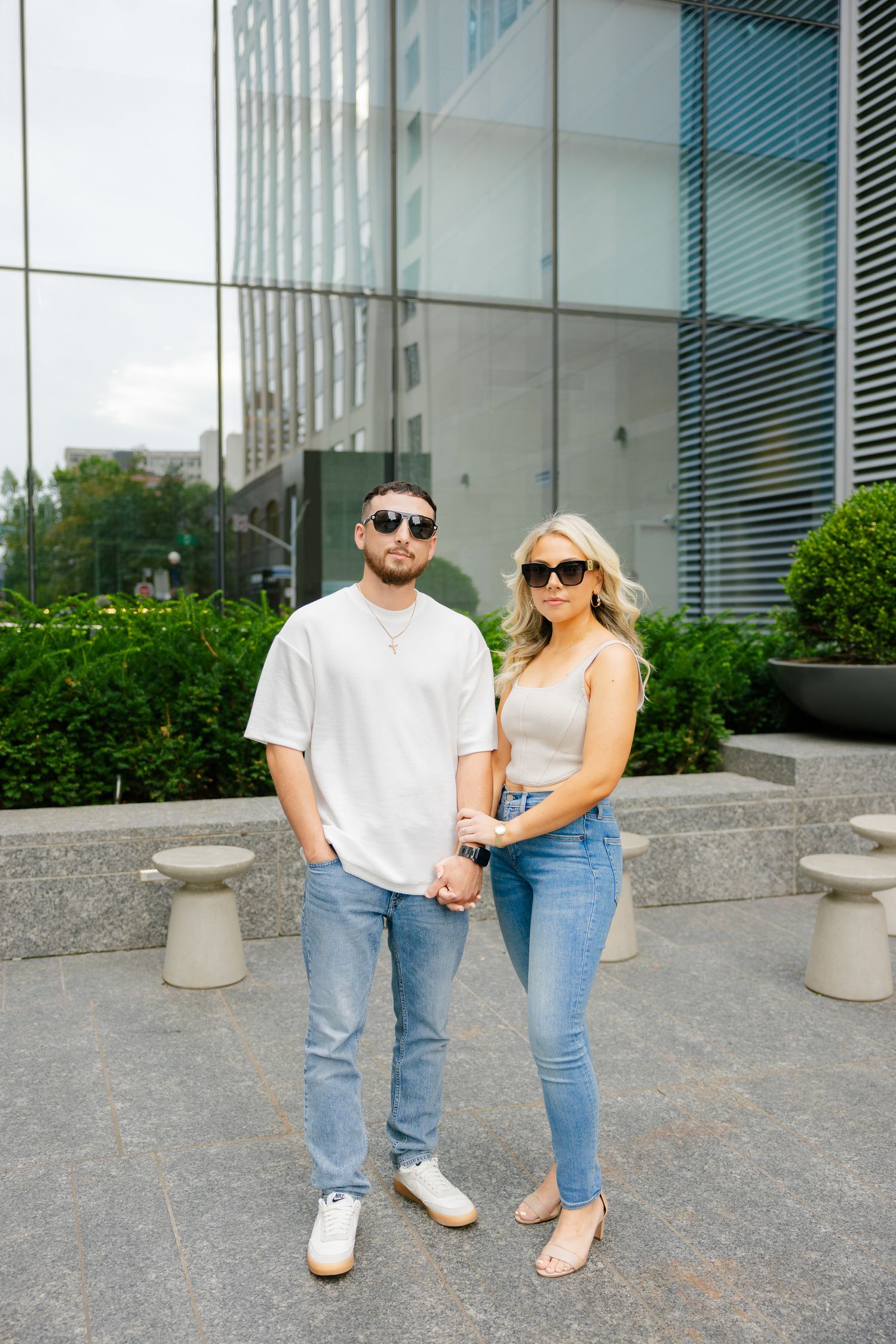A couple in coordinated casual outfits pose together on a city sidewalk.