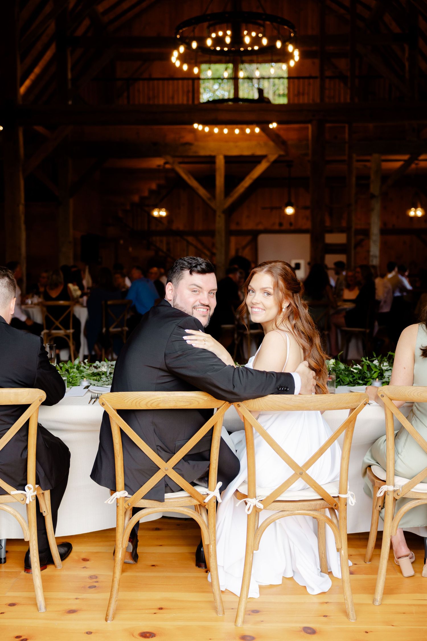 Wedding celebration in a barn venue with string lights and wooden beams creating a warm ambiance.